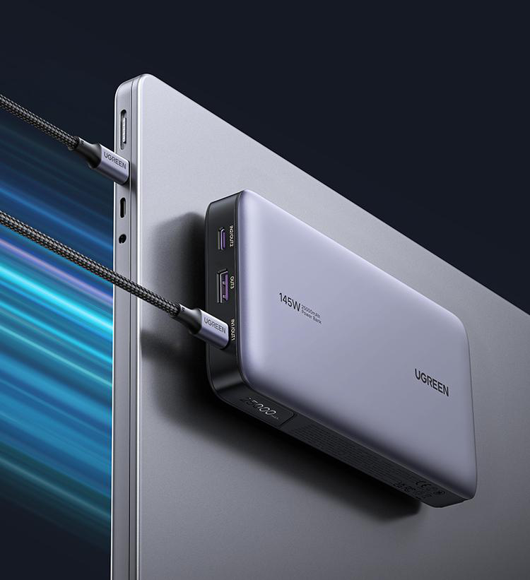 Silberne Powerbank, die mit schwarzen Kabeln an einen Laptop angeschlossen ist. UGREEN-Logo sichtbar.