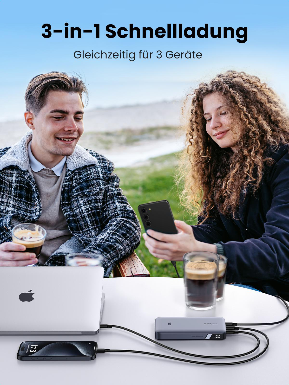 Zwei Personen benutzen Handys und einen Laptop, die alle von einer Powerbank geladen werden.