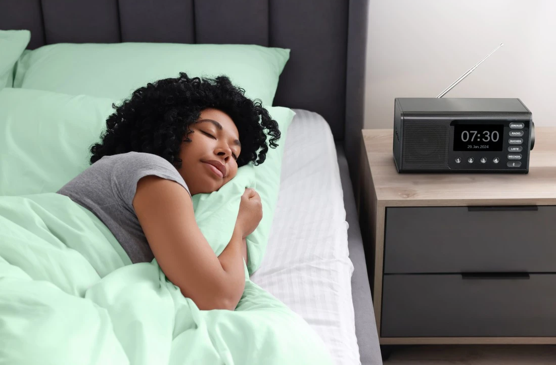 Donna che dorme a letto accanto a una sveglia digitale nera su un comodino.