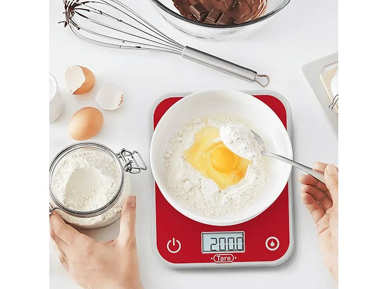Una báscula de cocina digital roja con harina, huevo y una cuchara encima.