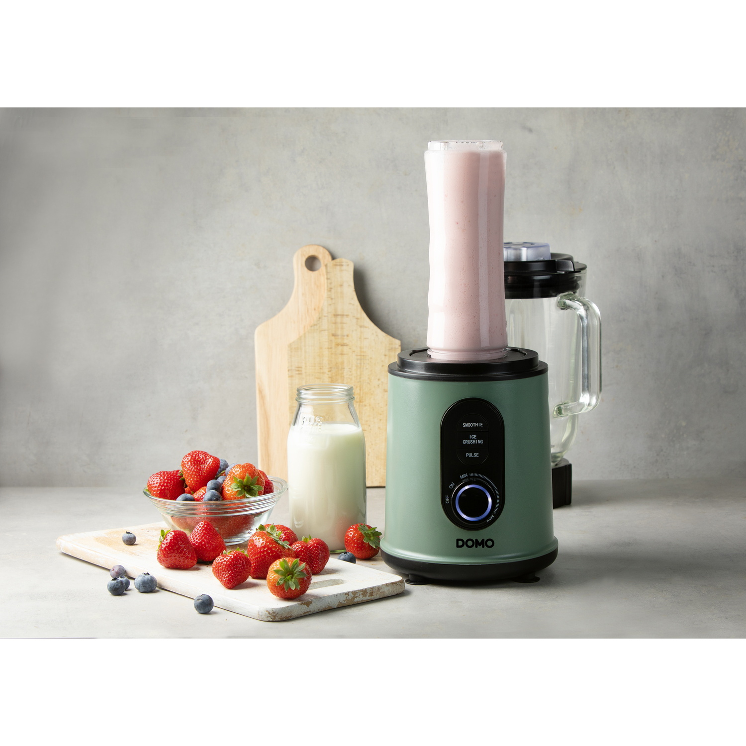 Blender vert avec smoothie rose, fraises, myrtilles et lait.
