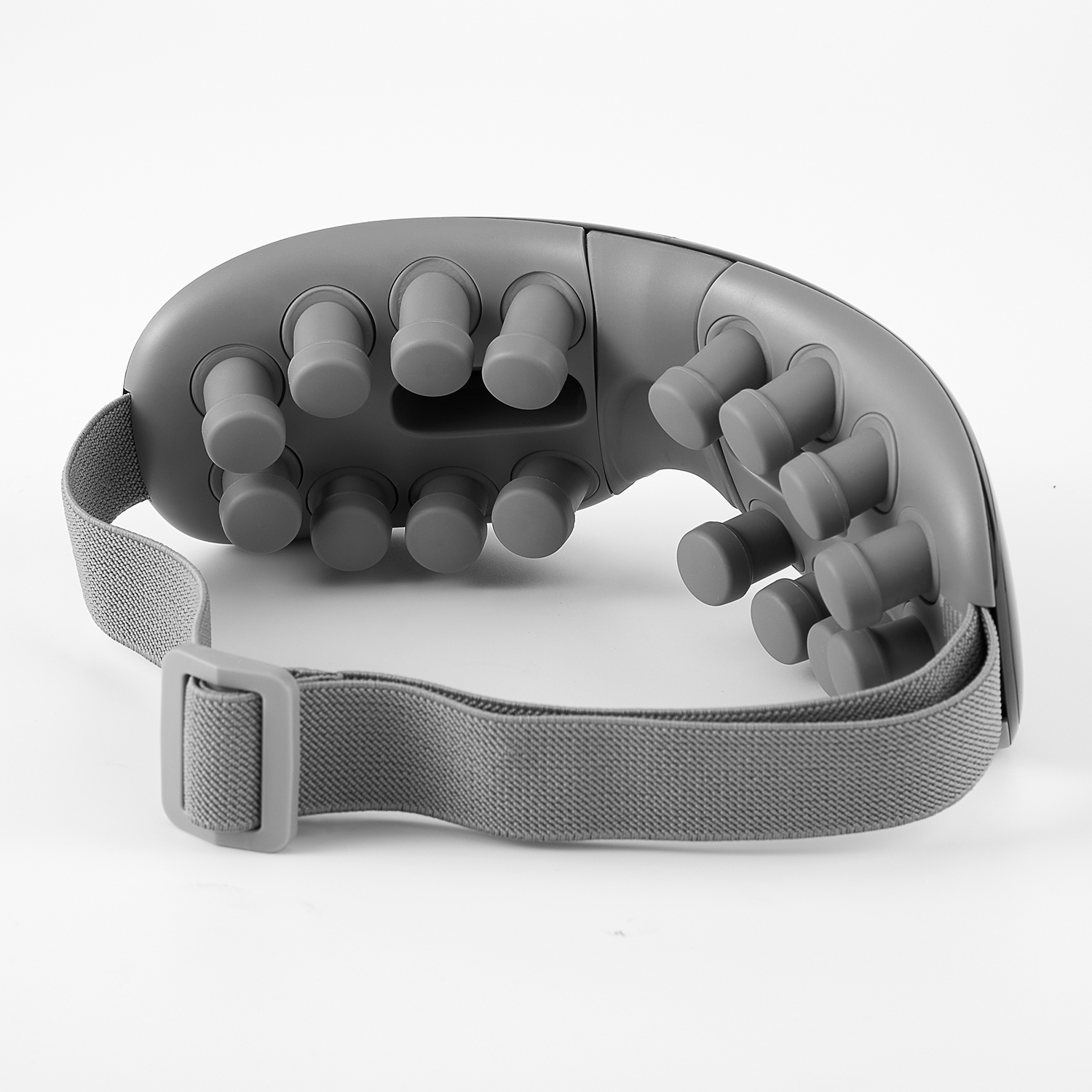 Gray eye massager on white background. Shows the massage nodes and strap.