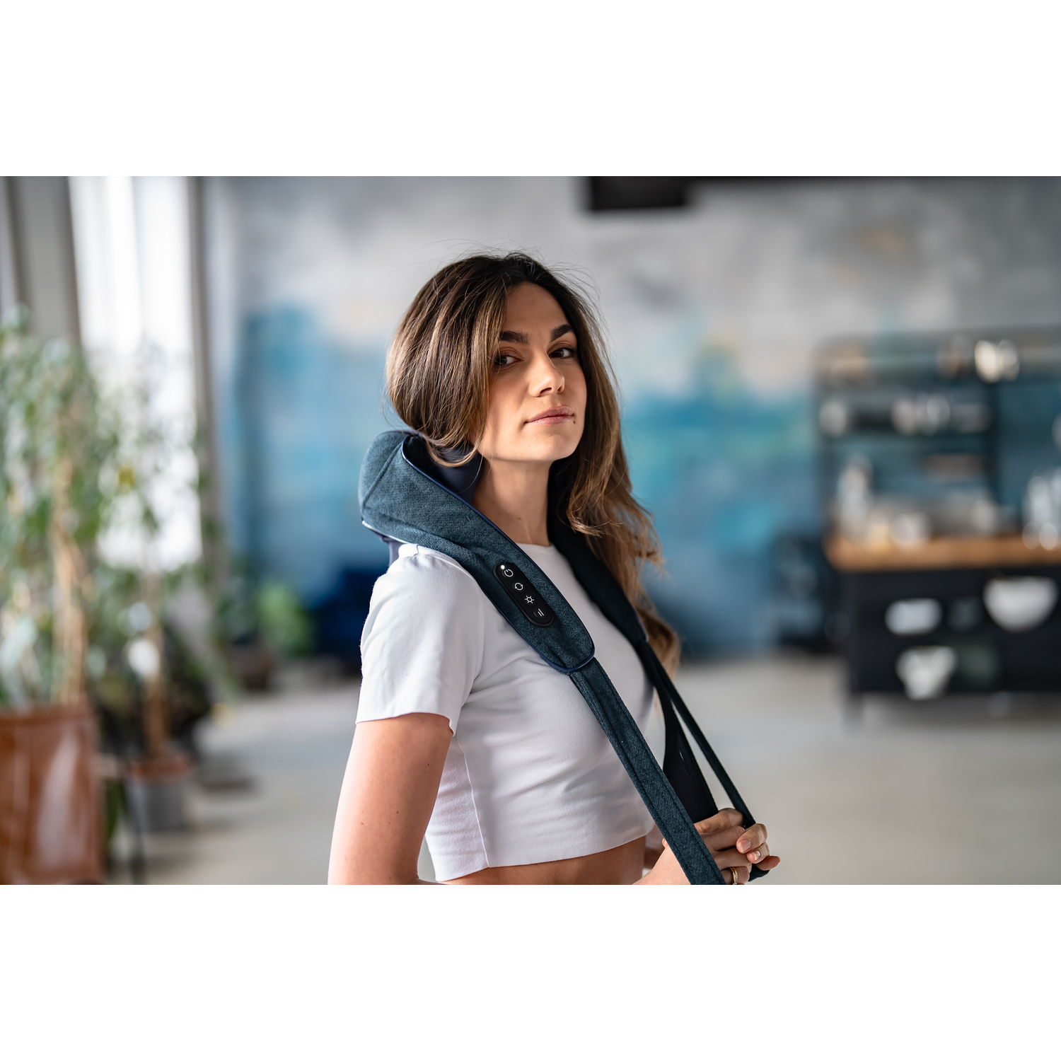 Woman wearing a blue massage device around her neck.