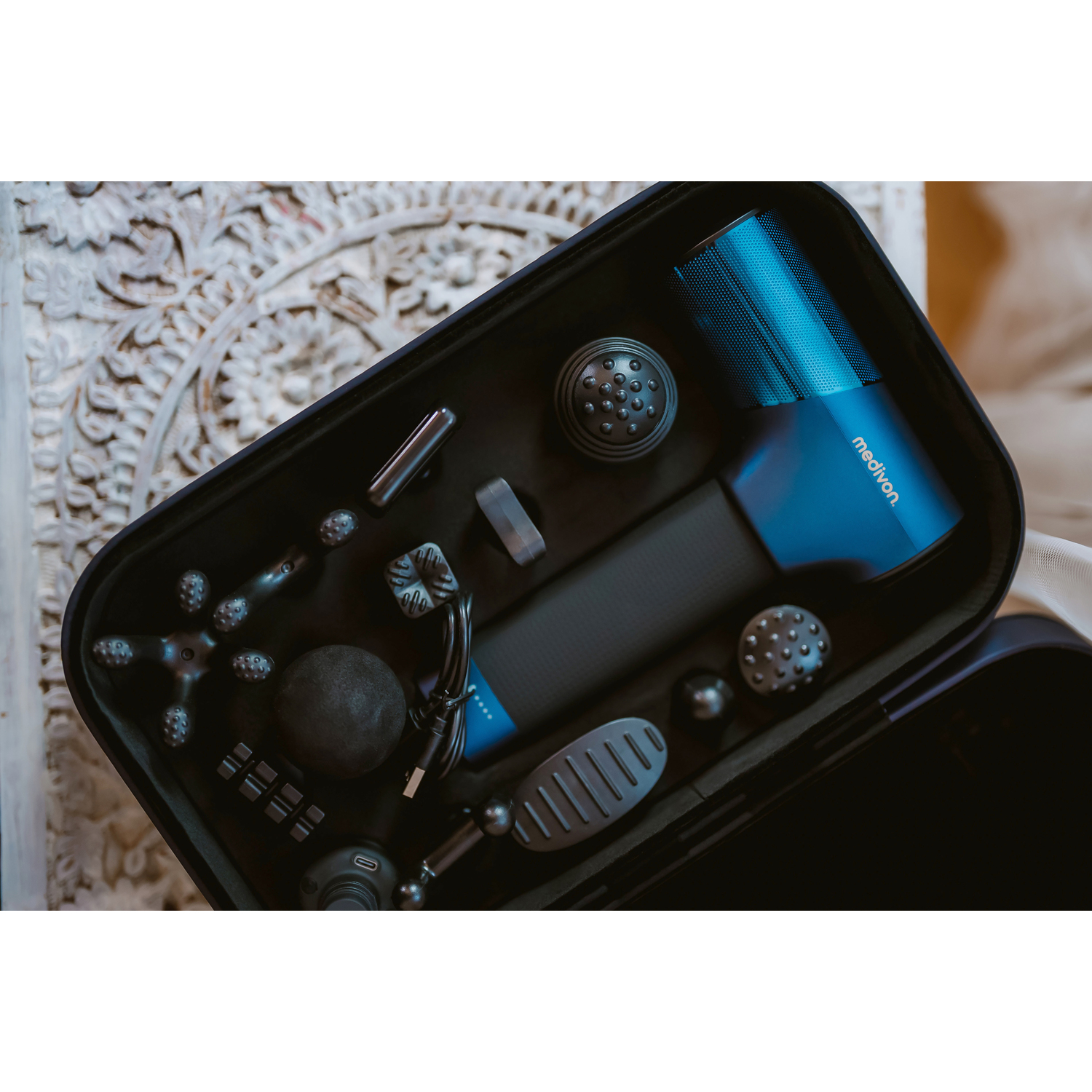Open black case with massage gun and attachments. All in dark blue.