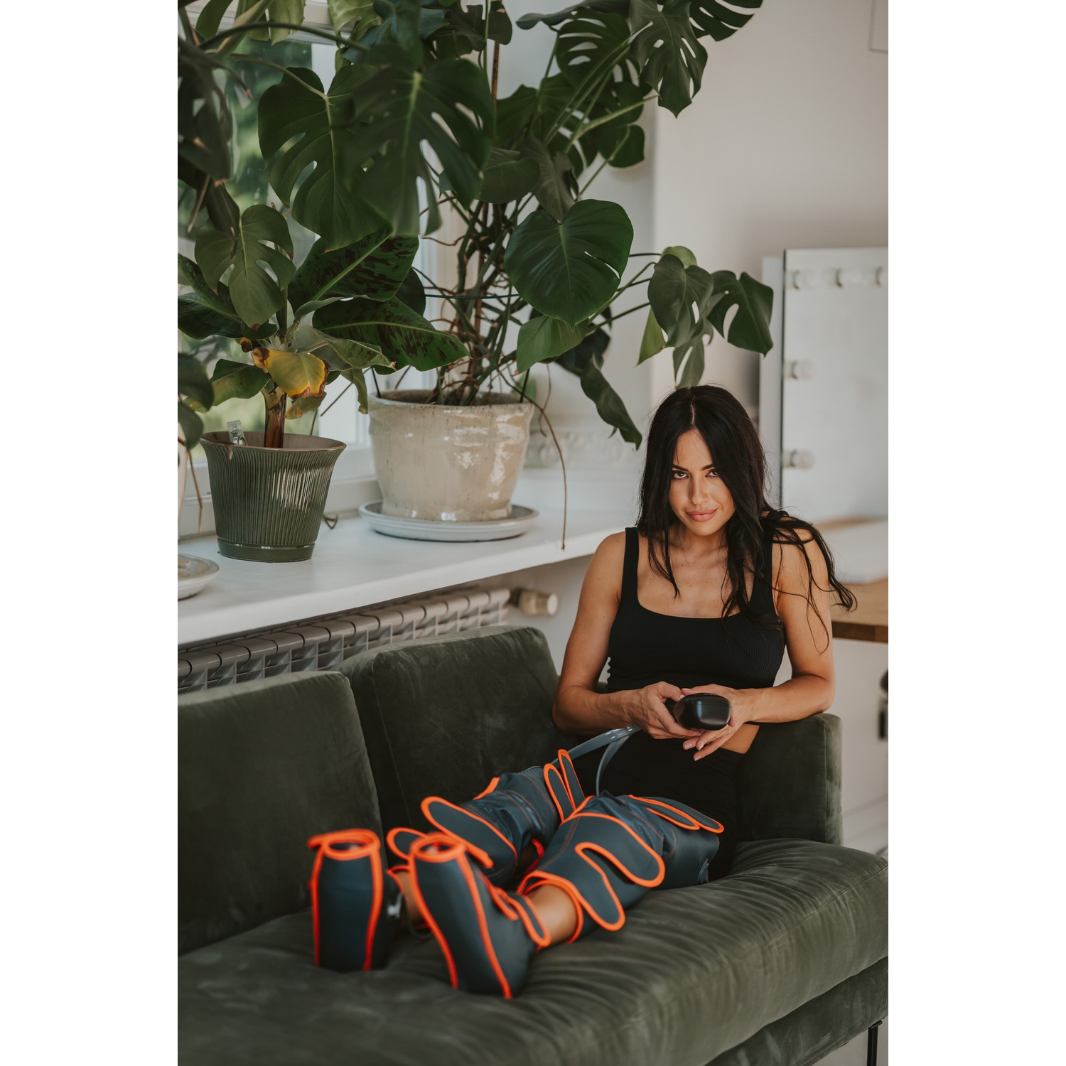 Woman sitting on a green couch with leg compression therapy devices.
