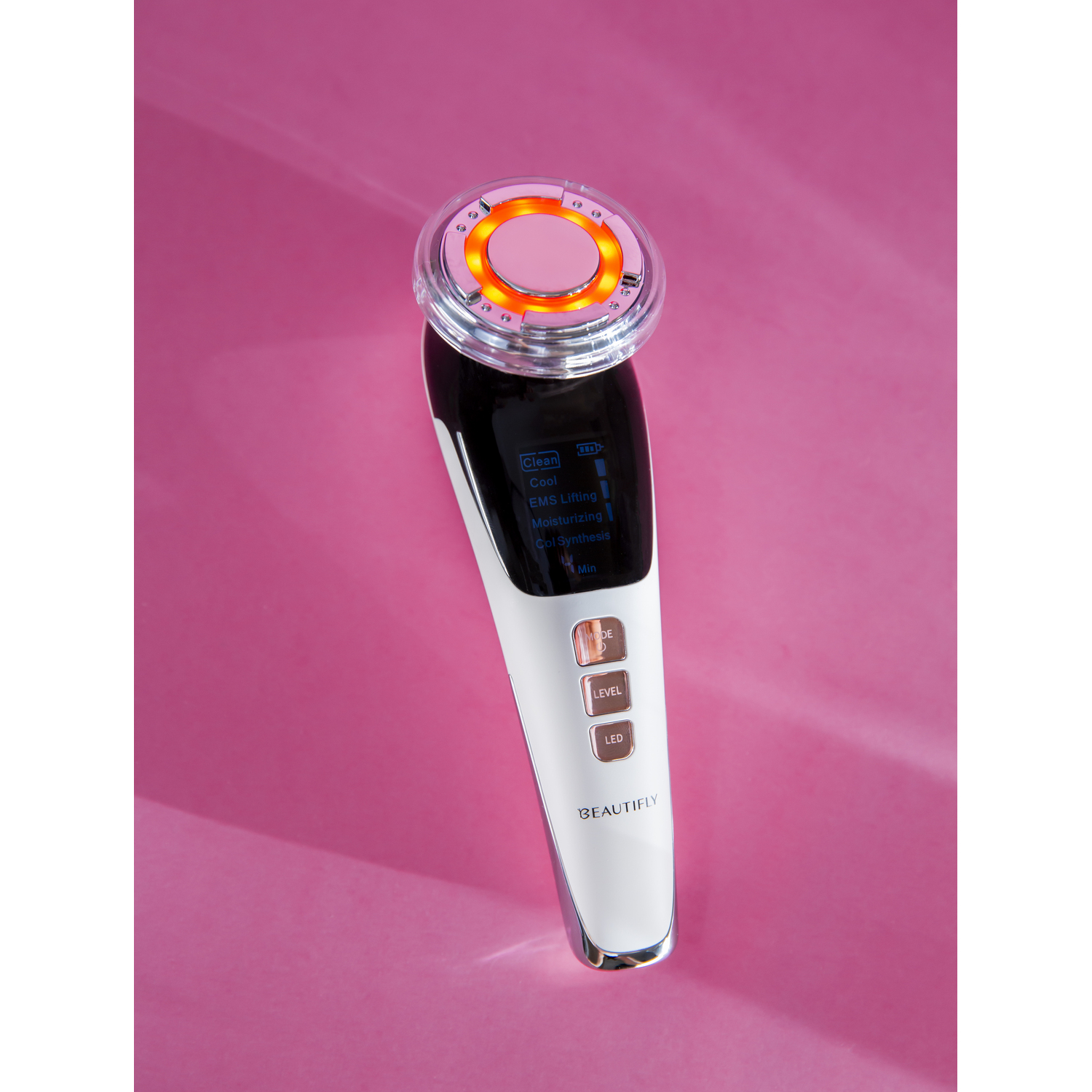 Beauty device with a glowing pink light on a pink background, displaying settings on screen.