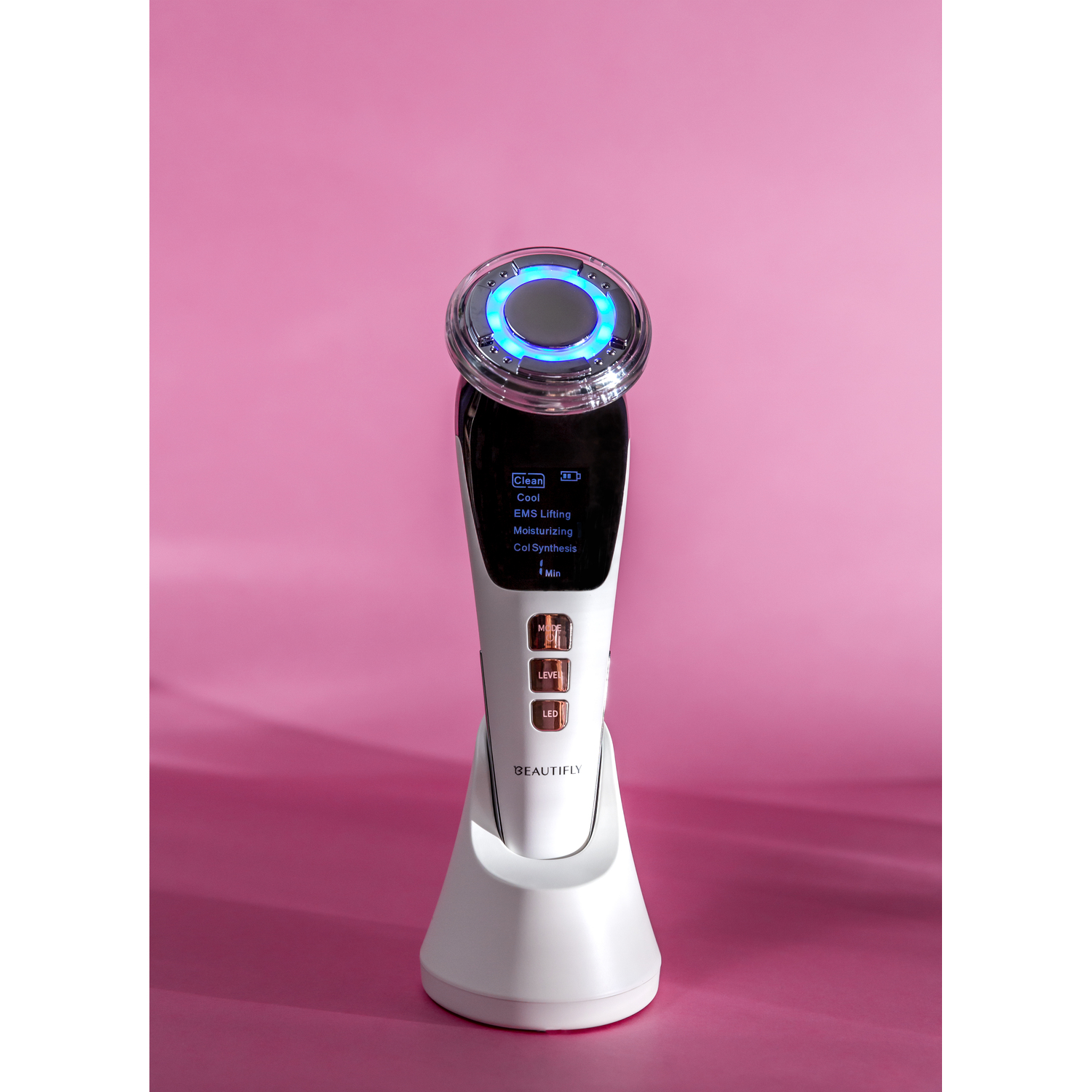 White and black facial device. Blue light on top. Display. Isolated on a pink background.