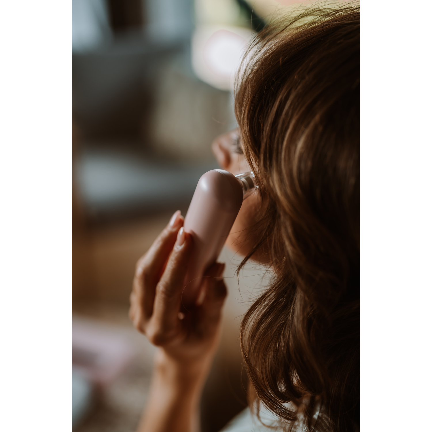 Woman using pink beauty device on her face, close-up shot. 