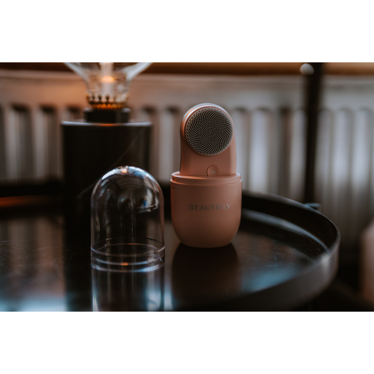 Pink beauty device and charging base on a black table. 