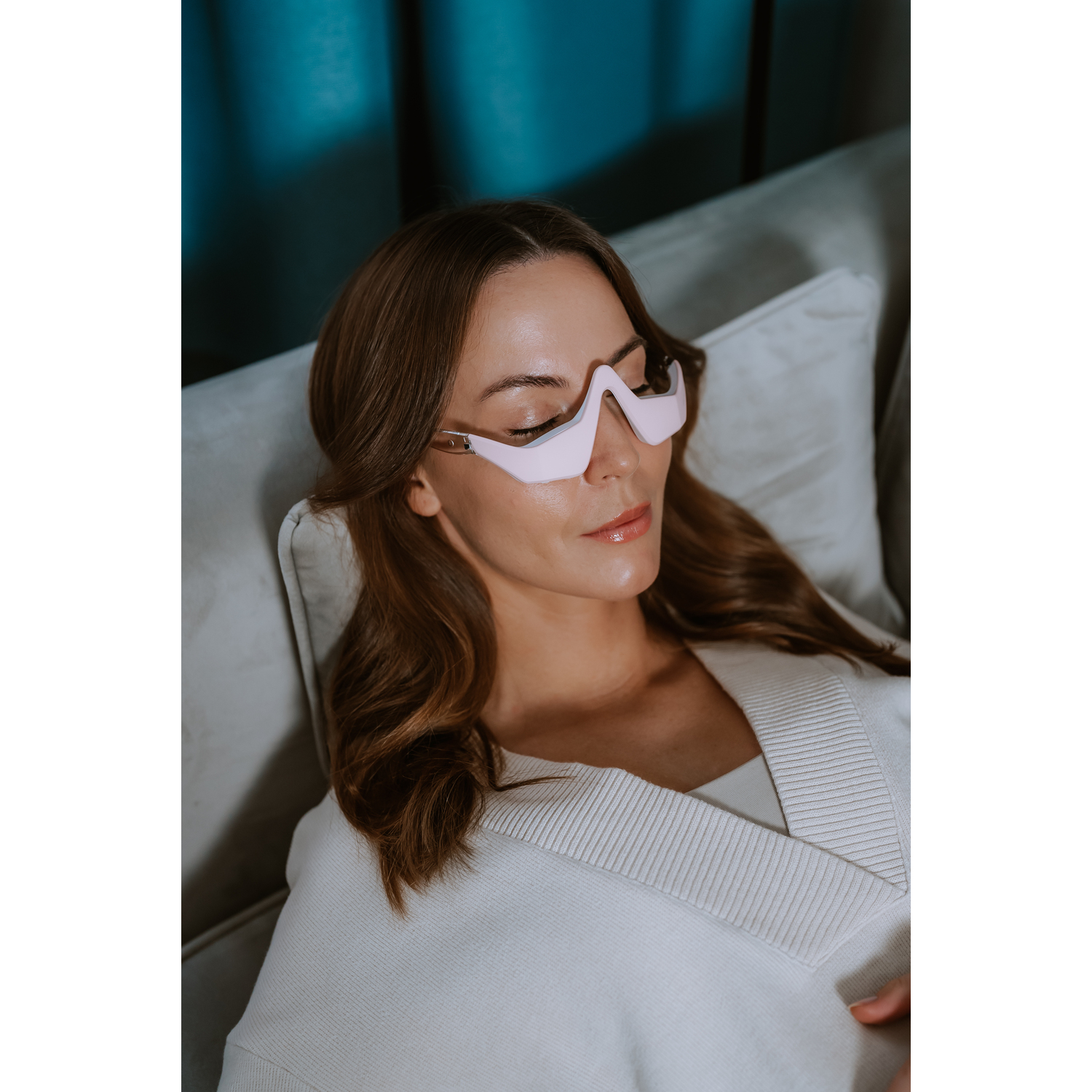 Woman wearing pink glasses, lying on a white couch.