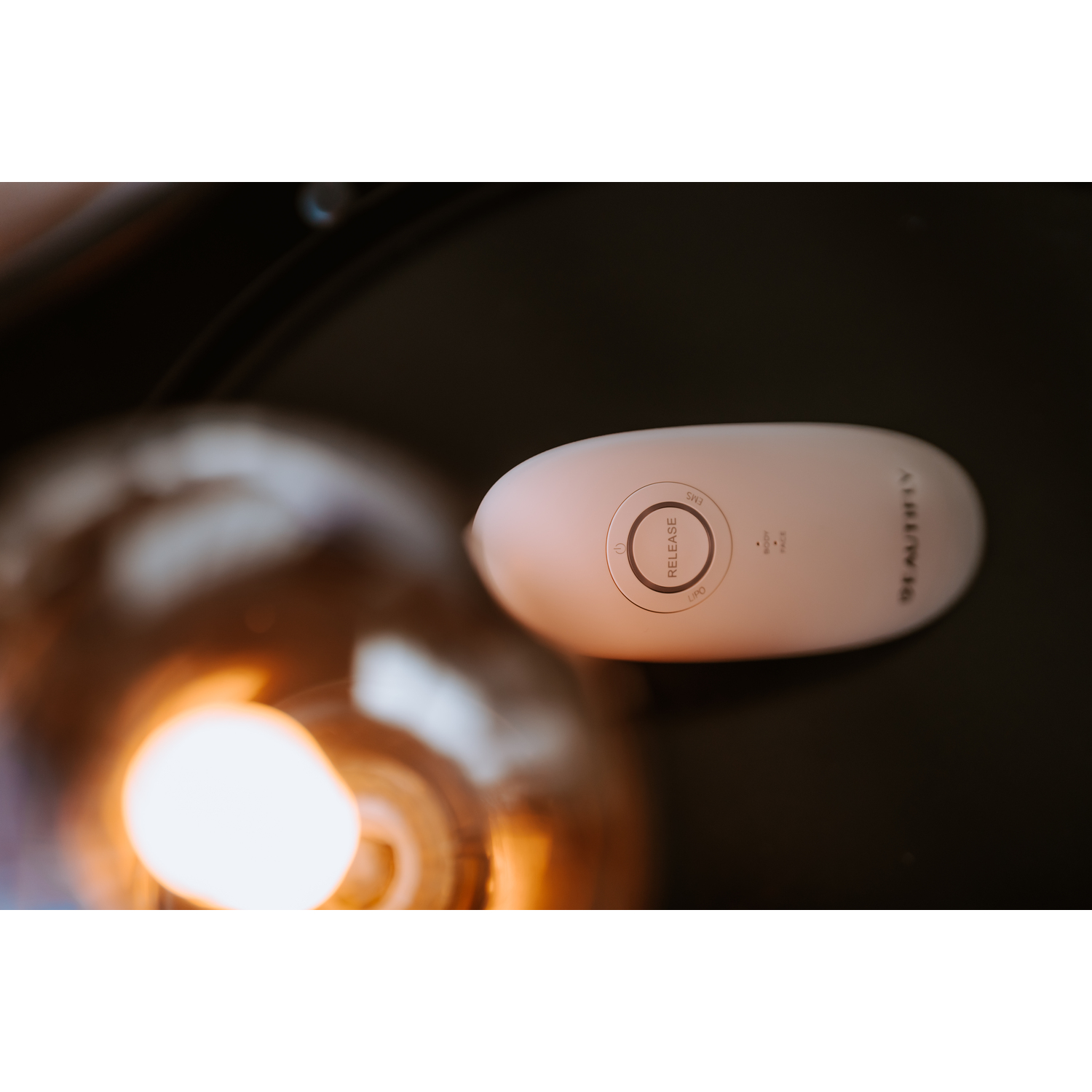 Een wit apparaat met een knop met het label 'RELEASE' op een zwart oppervlak met licht.