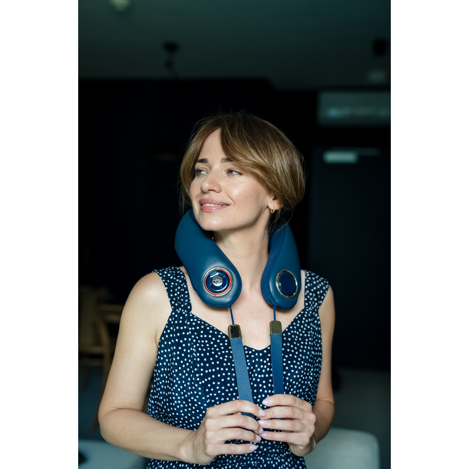 A woman wearing a blue neck massager. She is looking away.