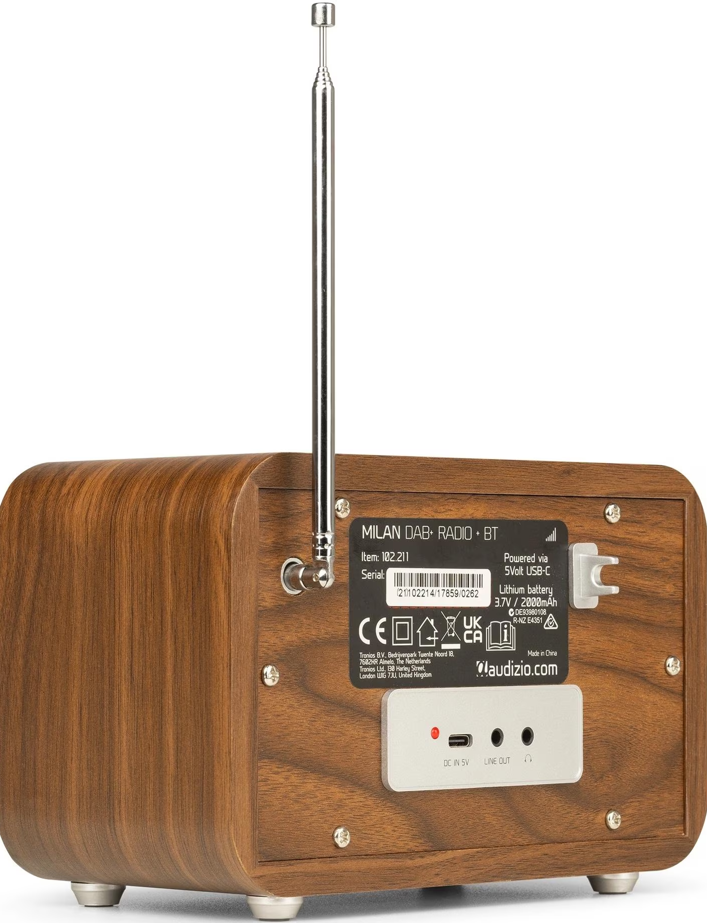 L'arrière d'une radio en bois. Antenne, étiquettes et entrées visibles. Pieds argentés le supportent.