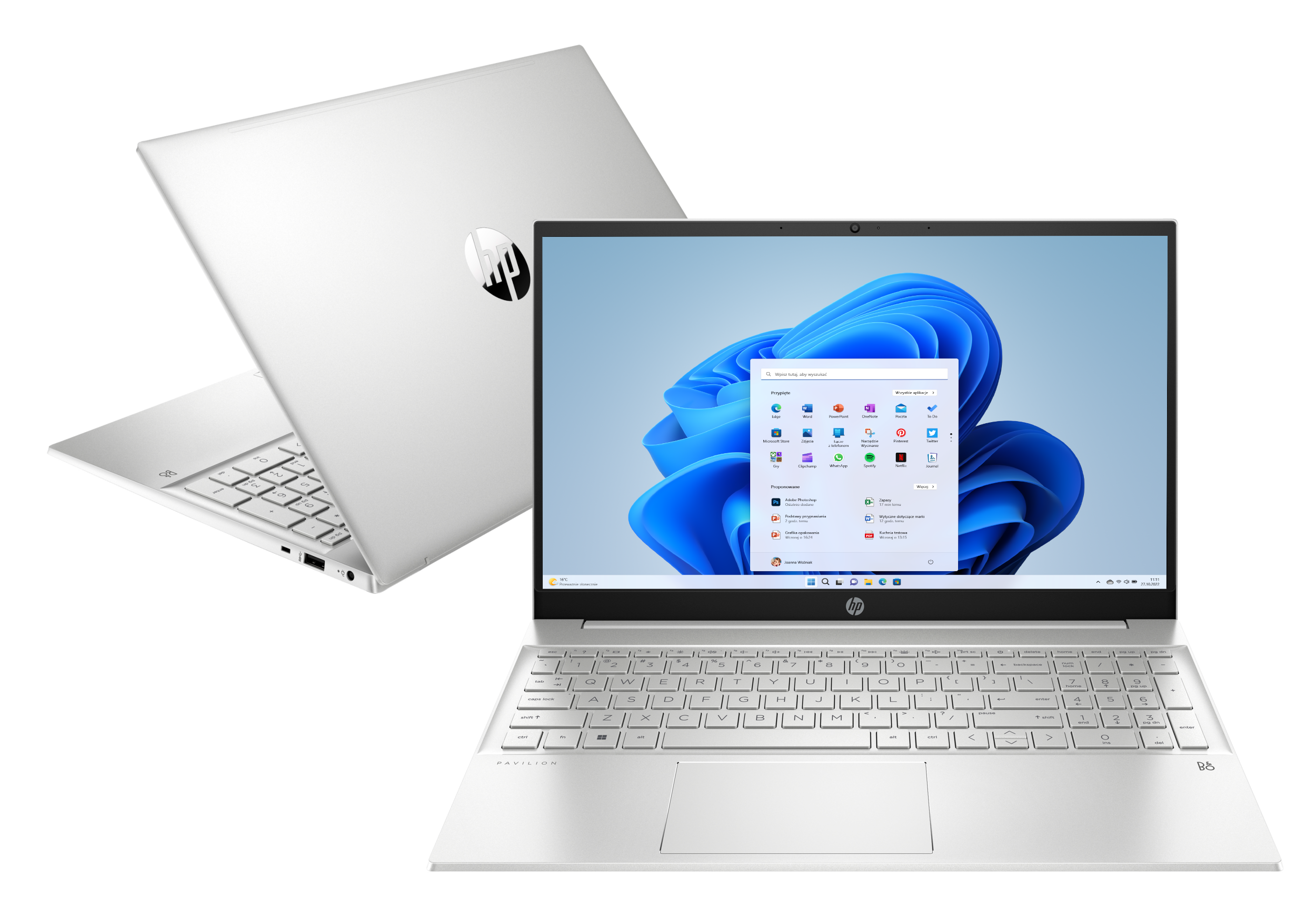 Dwa srebrne laptopy ułożone jeden na drugim. Górny laptop pokazuje ekran główny systemu Windows 11.