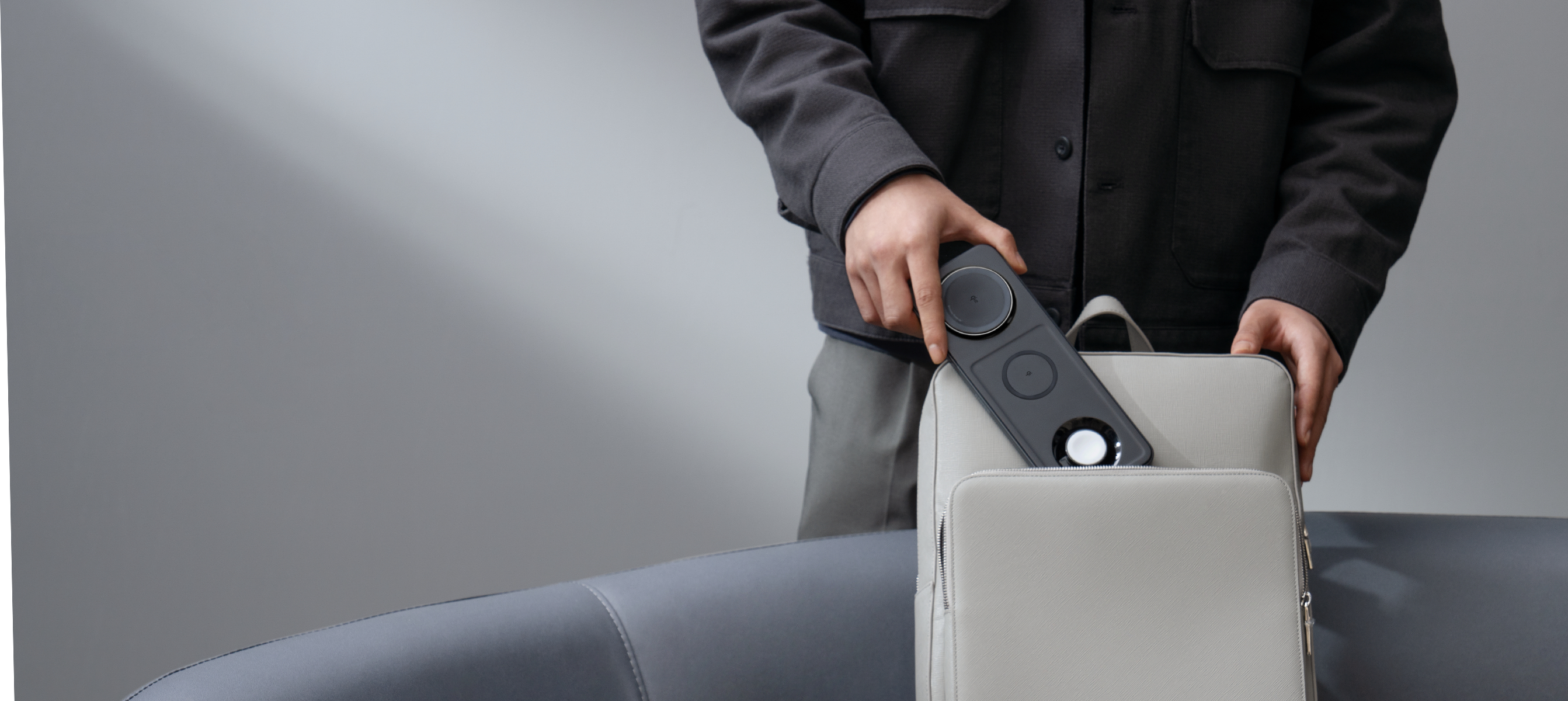 Person legt eine Ladestation mit Telefon und Uhr in eine Tasche.