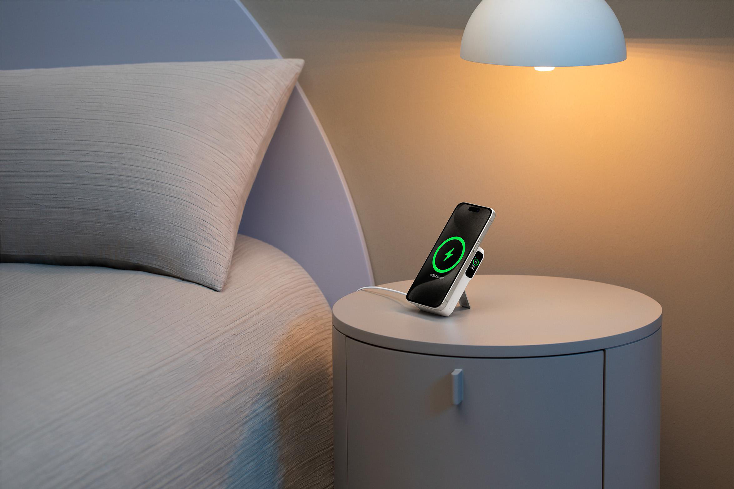 Ein Telefon, das auf einem Nachttisch neben einem Bett aufgeladen wird.