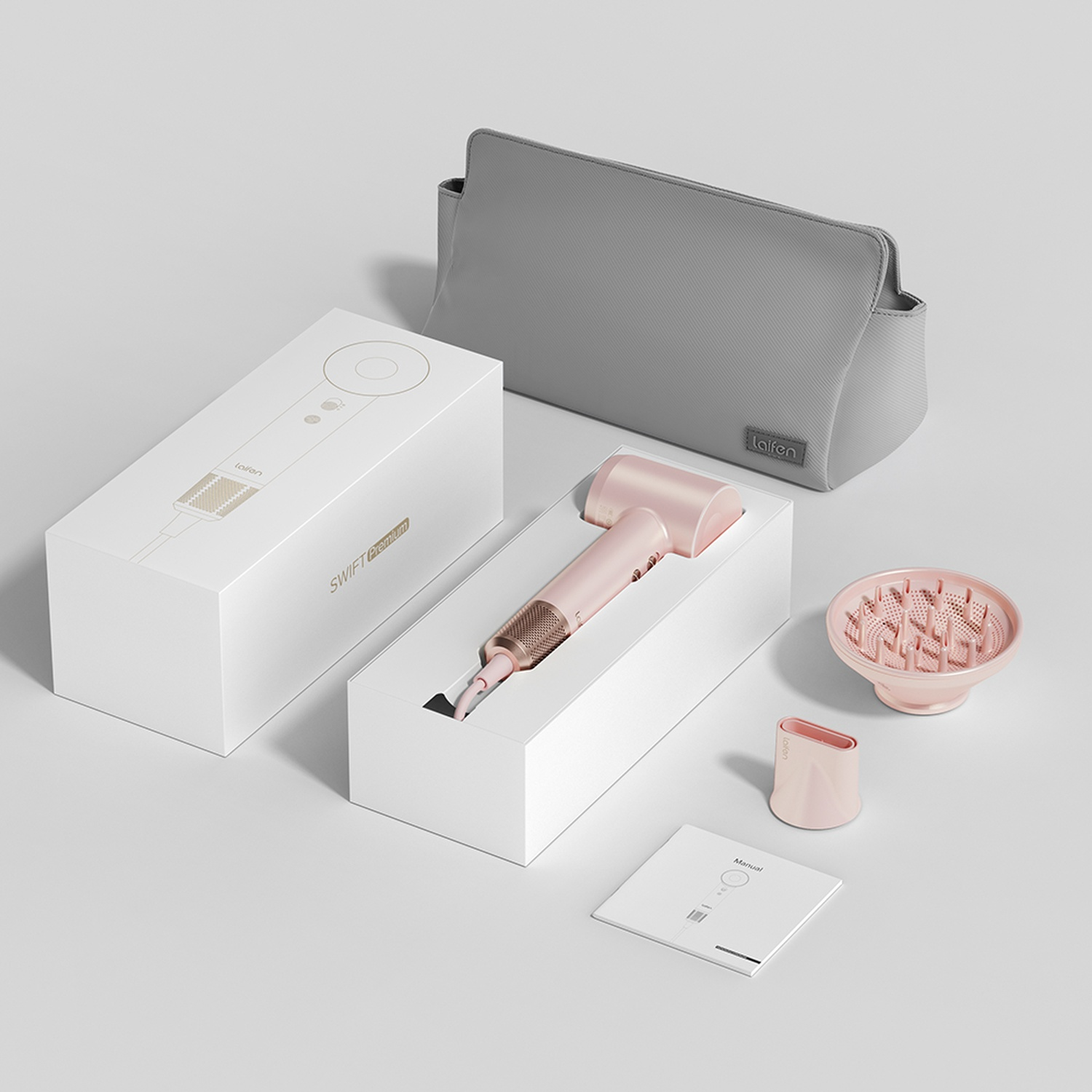 Una scatola bianca con un asciugacapelli rosa, accessori e una borsa grigia su sfondo bianco.