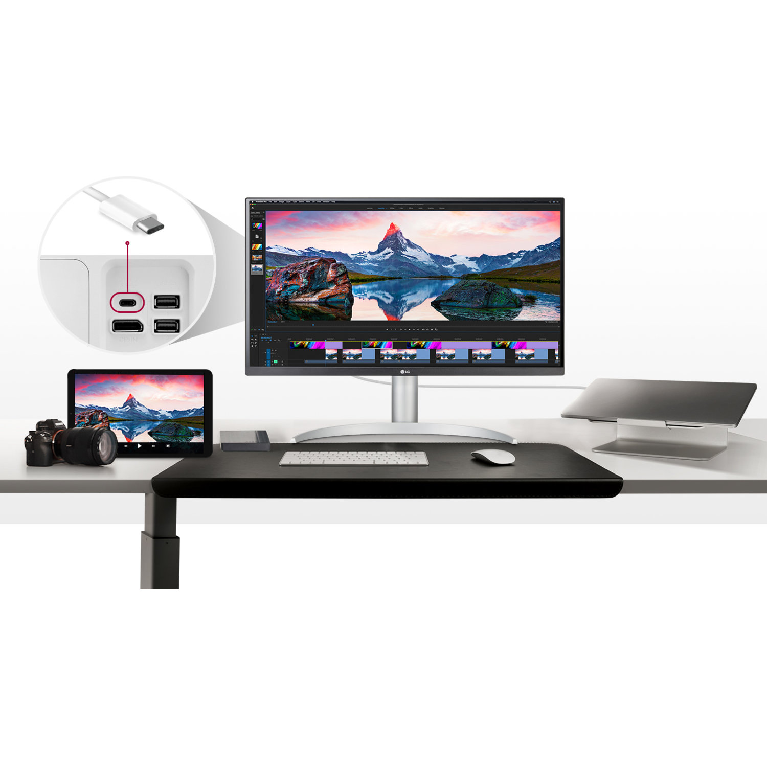 A monitor displays a mountain scene. A tablet, camera, and laptop are on the desk. USB ports are highlighted. 