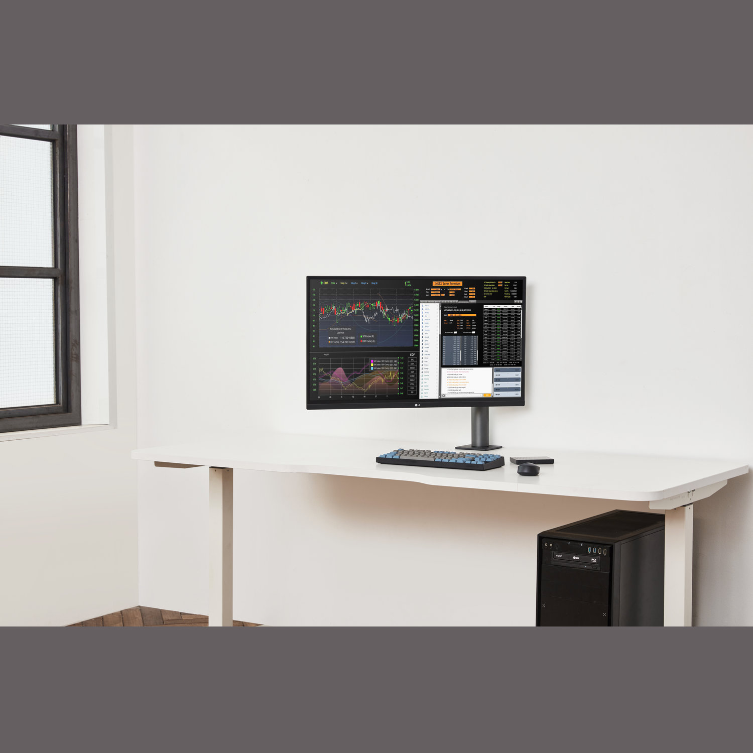 Een bureau met een computermonitor waarop aandelenkoersen worden weergegeven. Een toetsenbord, muis en computertoren staan ook op het bureau.