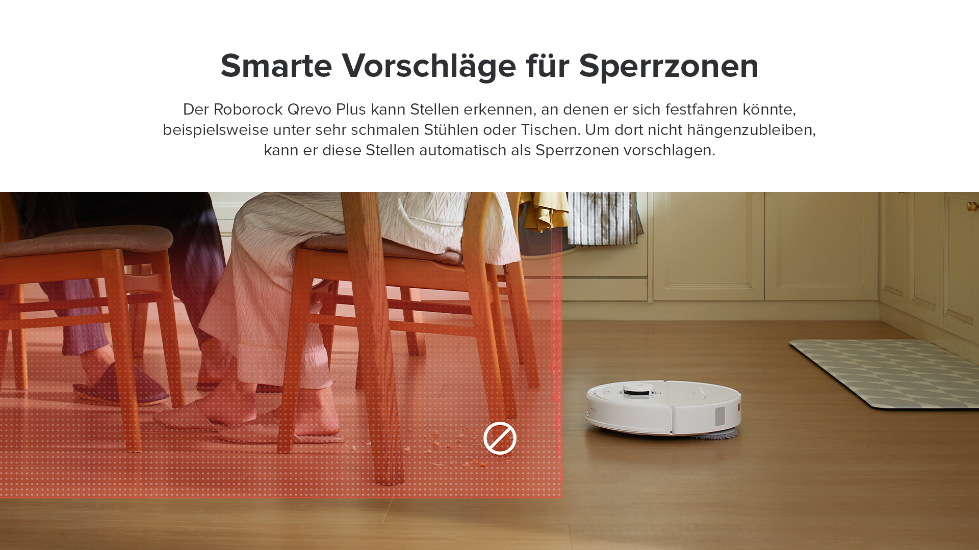 Ein Roboter-Staubsauger auf einem Holzboden, in der Nähe einer roten Zone, die für Bereiche unter Stühlen gekennzeichnet ist.
