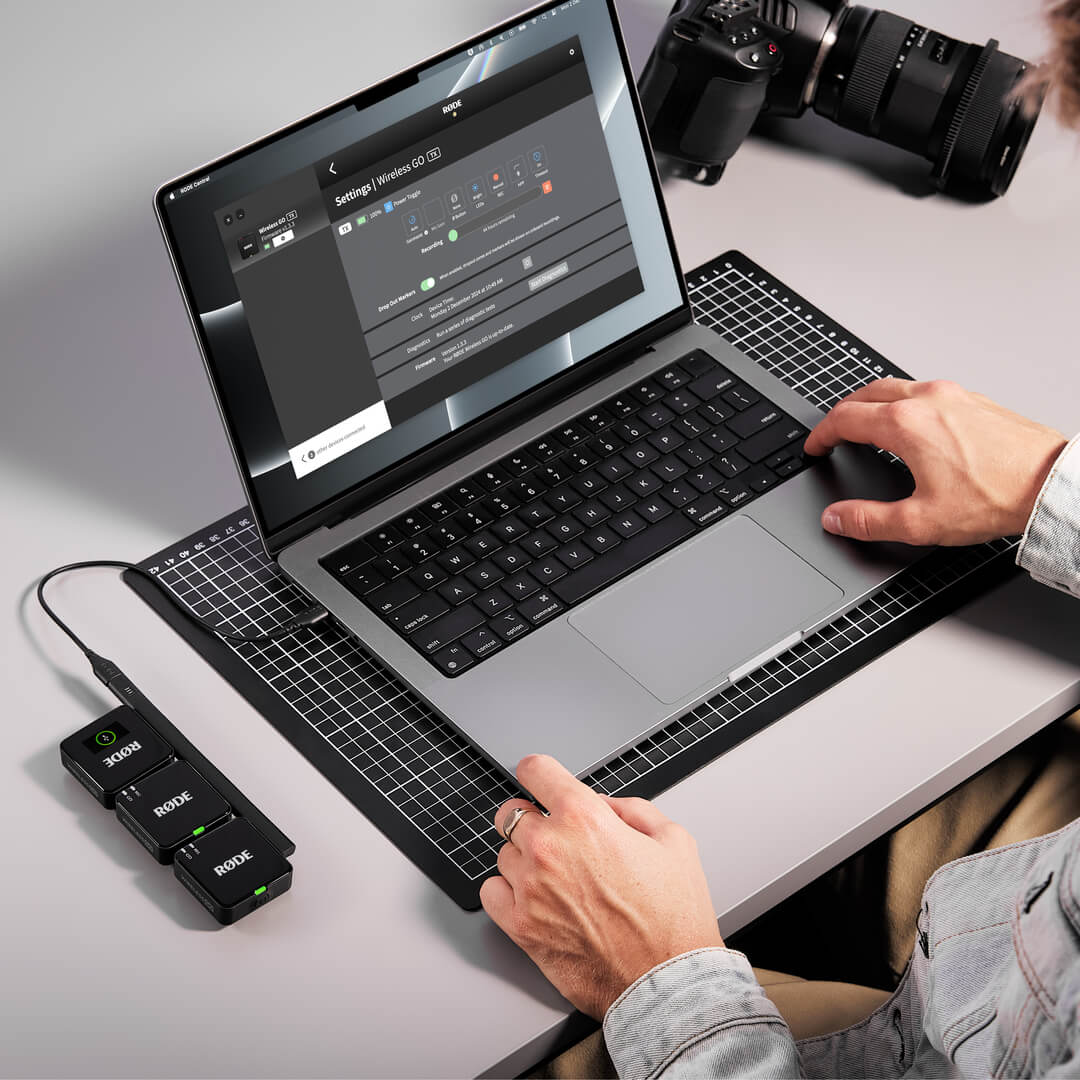 Ordinateur portable sur un bureau avec équipement audio et mains interagissant.