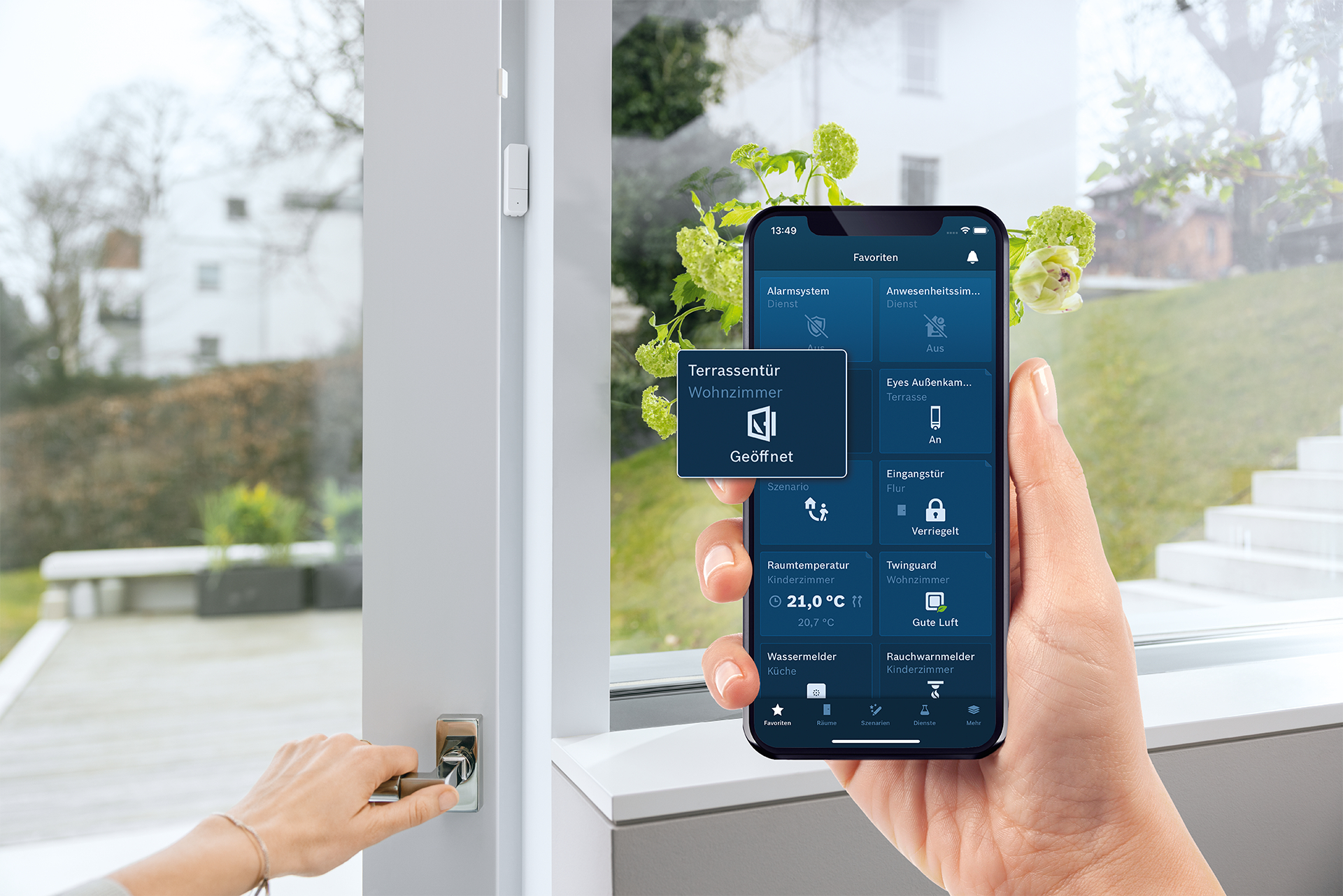 Hand hält Handy mit Smart-Home-App, Türgriff und Fenster.