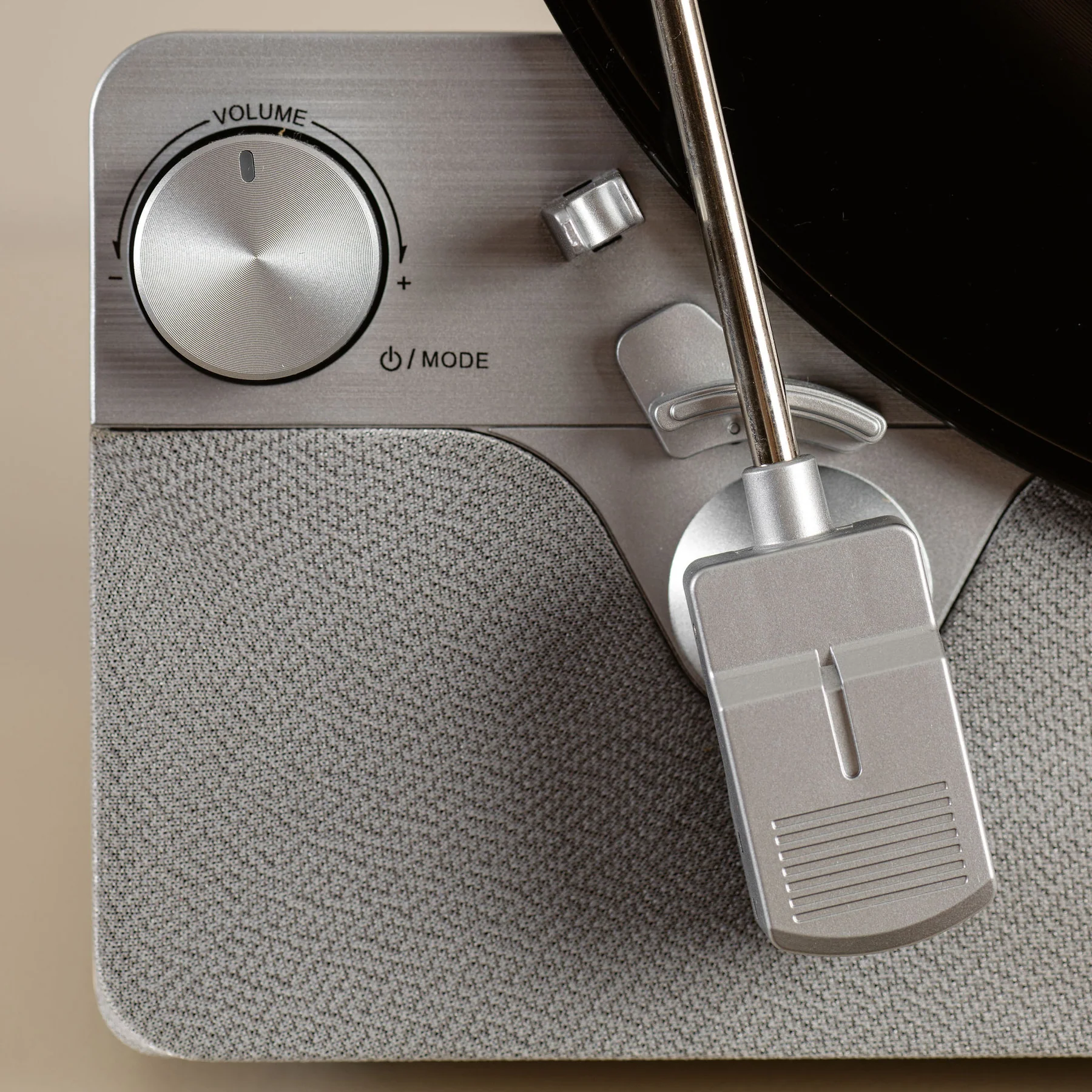 Gros plan sur les commandes du tourne-disque : volume et mode. Une aiguille est sur un disque.