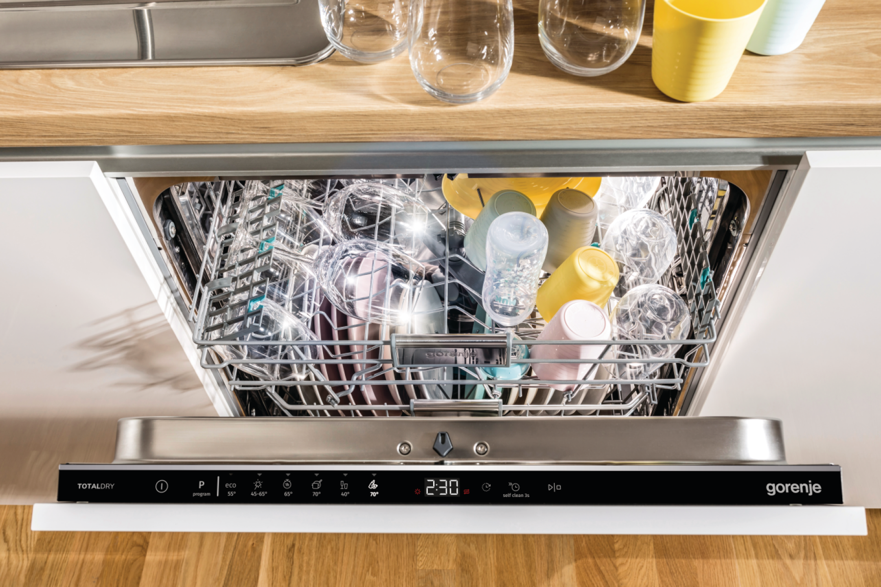 Egy Gorenje mosogatógép belseje edényekkel. A belső térben poharak, csészék és egyéb tárgyak láthatók a tartókban.