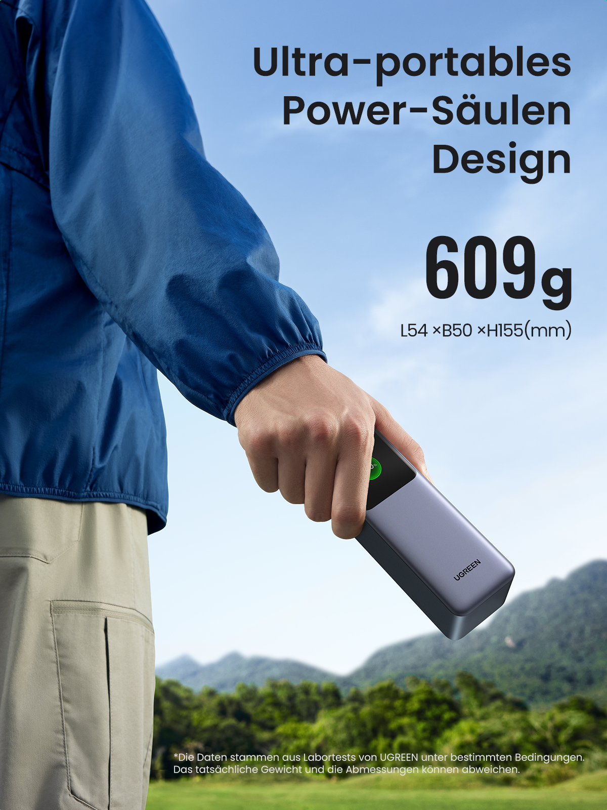 Eine Person hält eine kleine, dunkelgraue UGREEN Powerbank mit einem grünen Knopf.