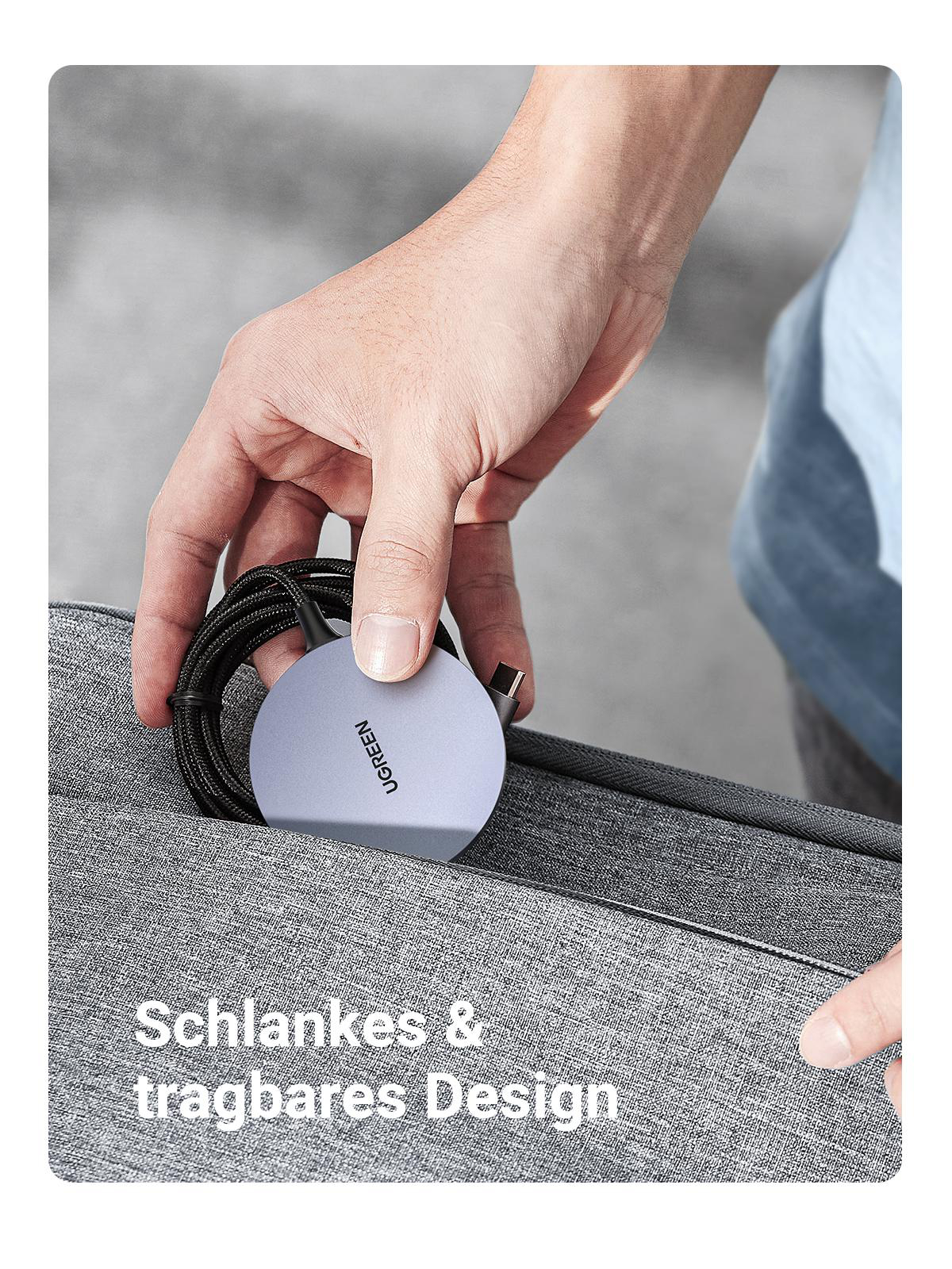 Eine Hand hält ein graues, kreisförmiges UGREEN-Ladegerät und steckt es in eine Tasche.