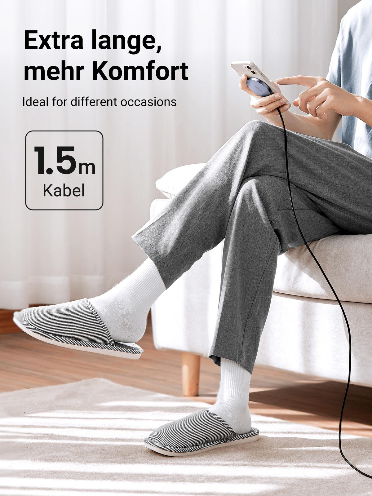 Mann in Hausschuhen lädt Telefon mit Kabel auf.