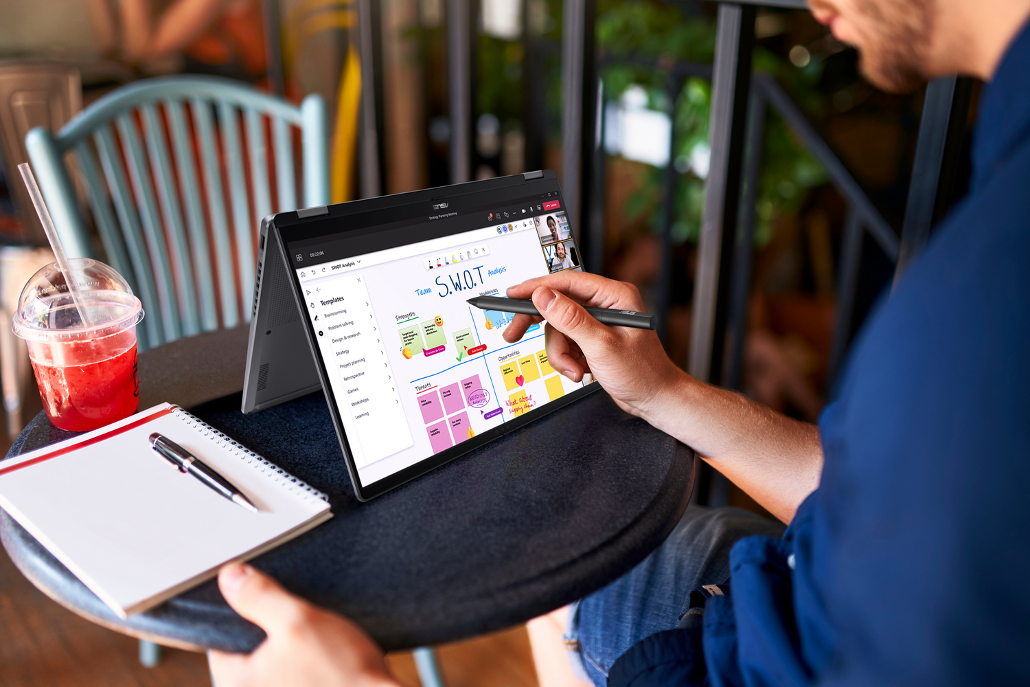 Una persona usando una laptop, con un bolígrafo, en un café.