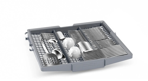 Una cesta gris de lavavajillas llena de cubiertos, dos tazas y utensilios de cocina, sobre fondo blanco.