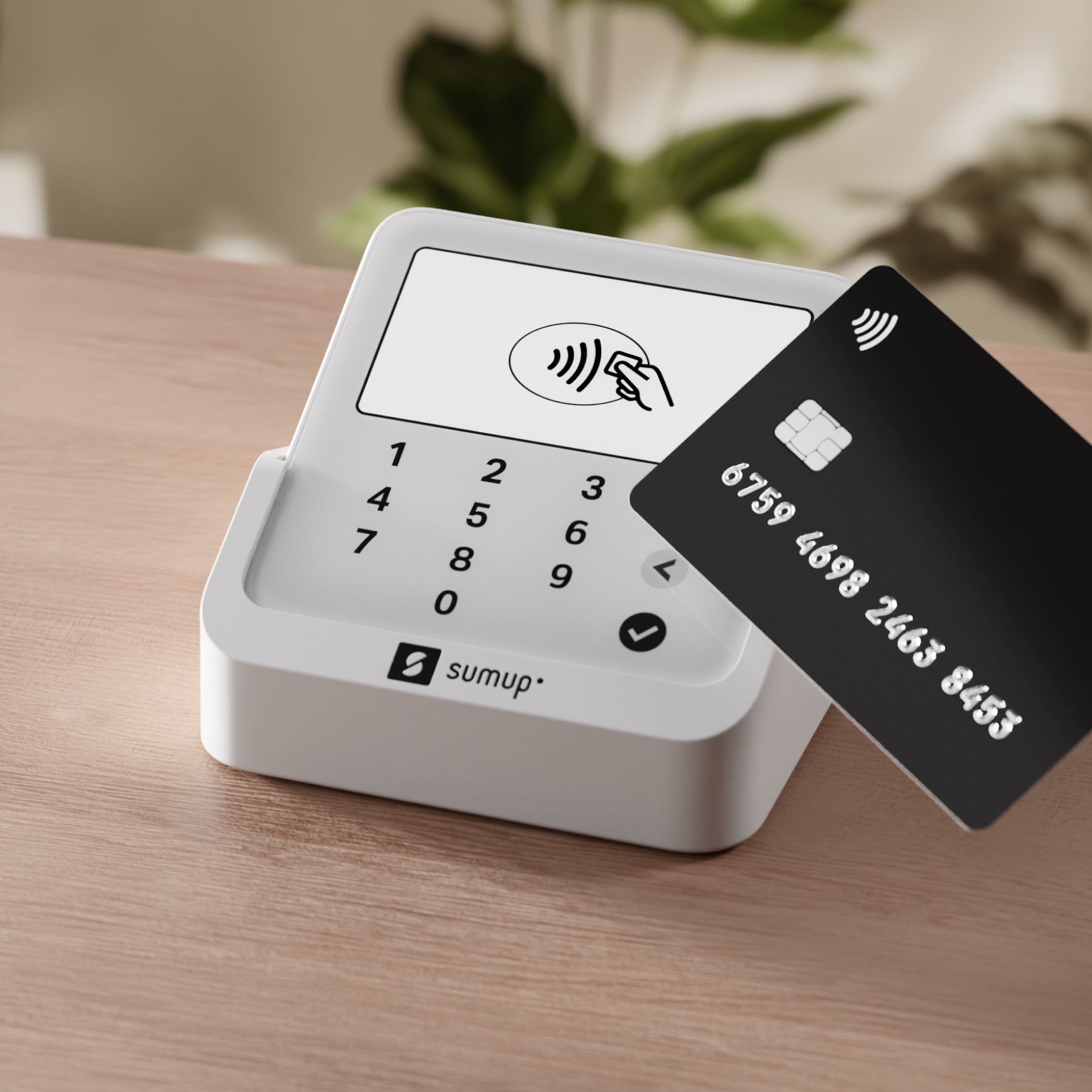Un terminale di pagamento bianco con una carta di credito nera accanto.