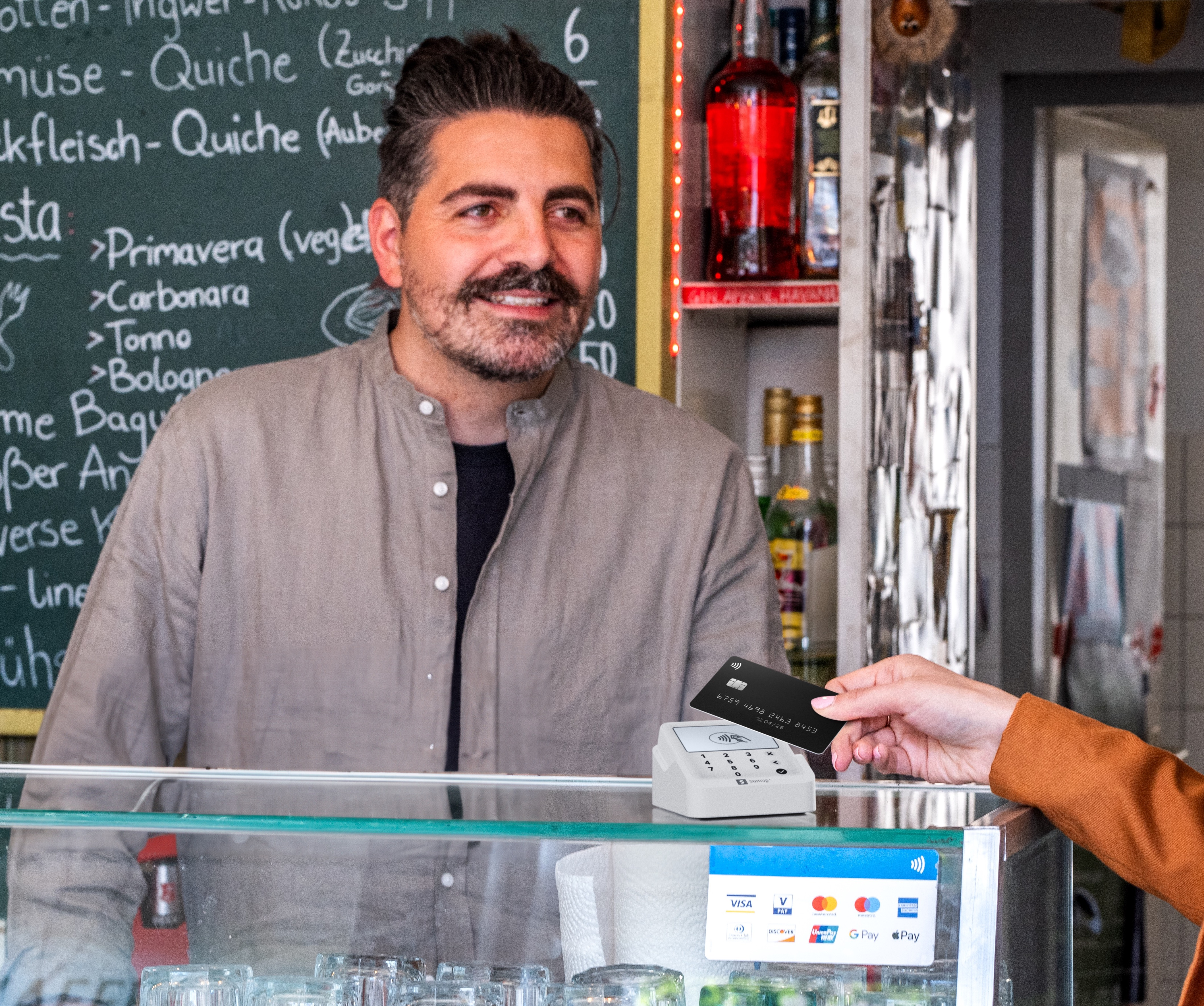 Un uomo dietro un bancone riceve una carta di credito per effettuare un acquisto.