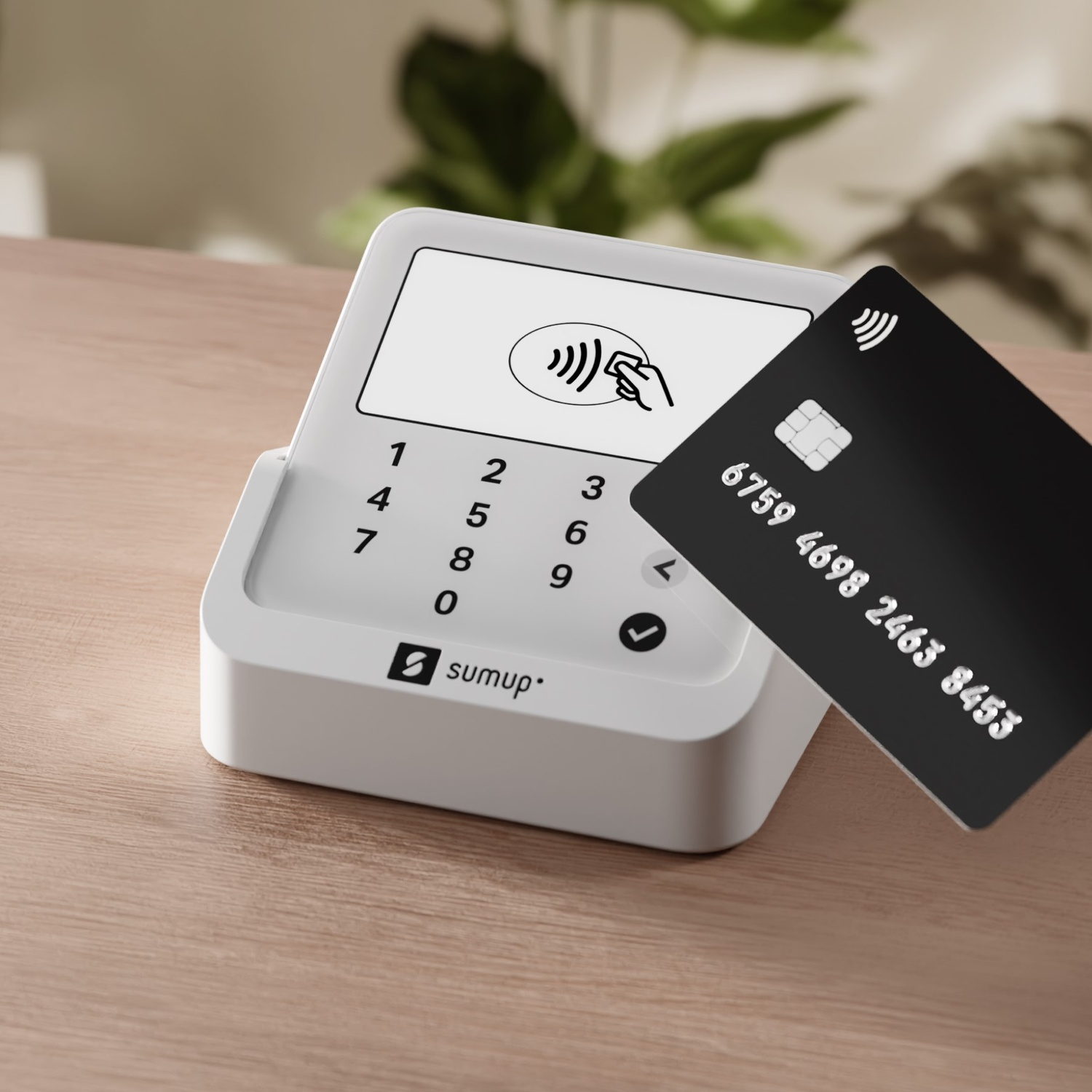 Terminal di pagamento bianco con carta di credito accanto, su superficie in legno.