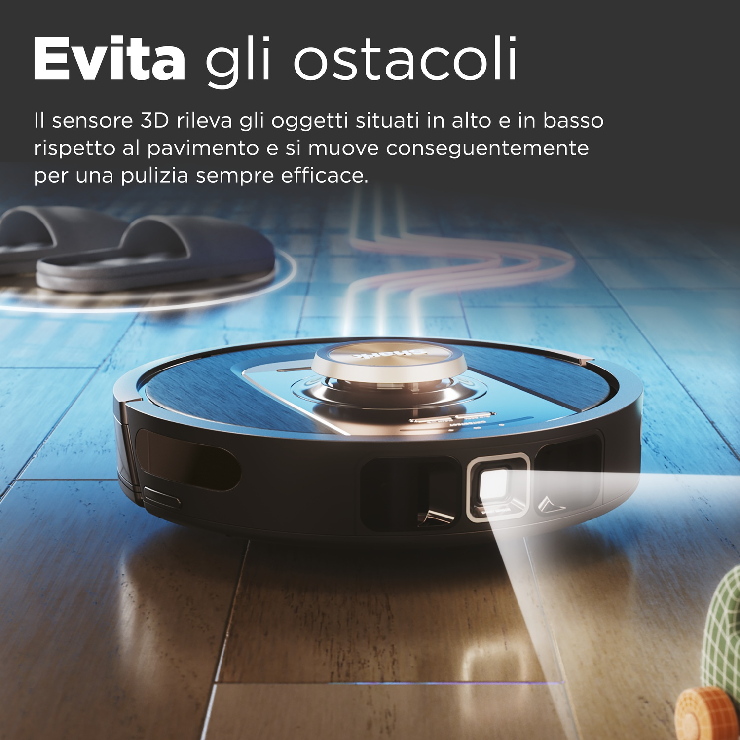 Un aspirapolvere robot evita gli ostacoli. Una scarpa e una pantofola sullo sfondo. Il pavimento è in legno.