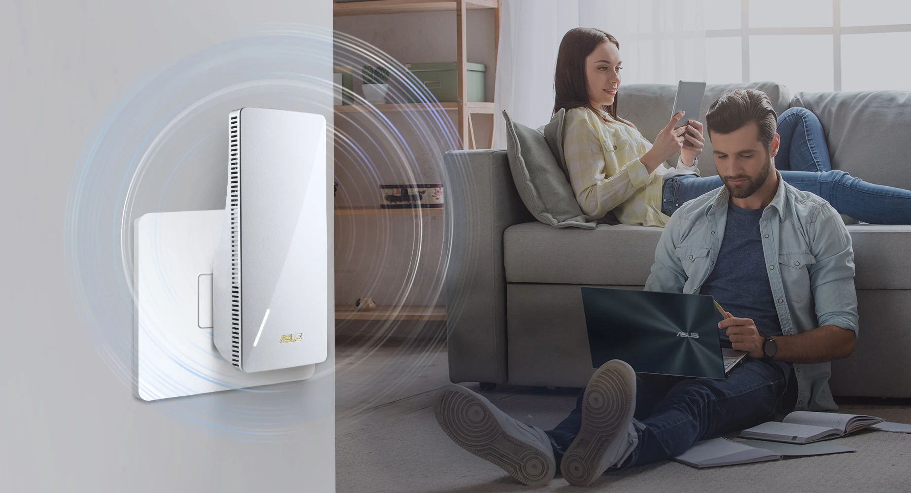 Mężczyzna siedzi na podłodze i używa laptopa, dwie osoby na kanapie i wzmacniacz Wi-Fi.