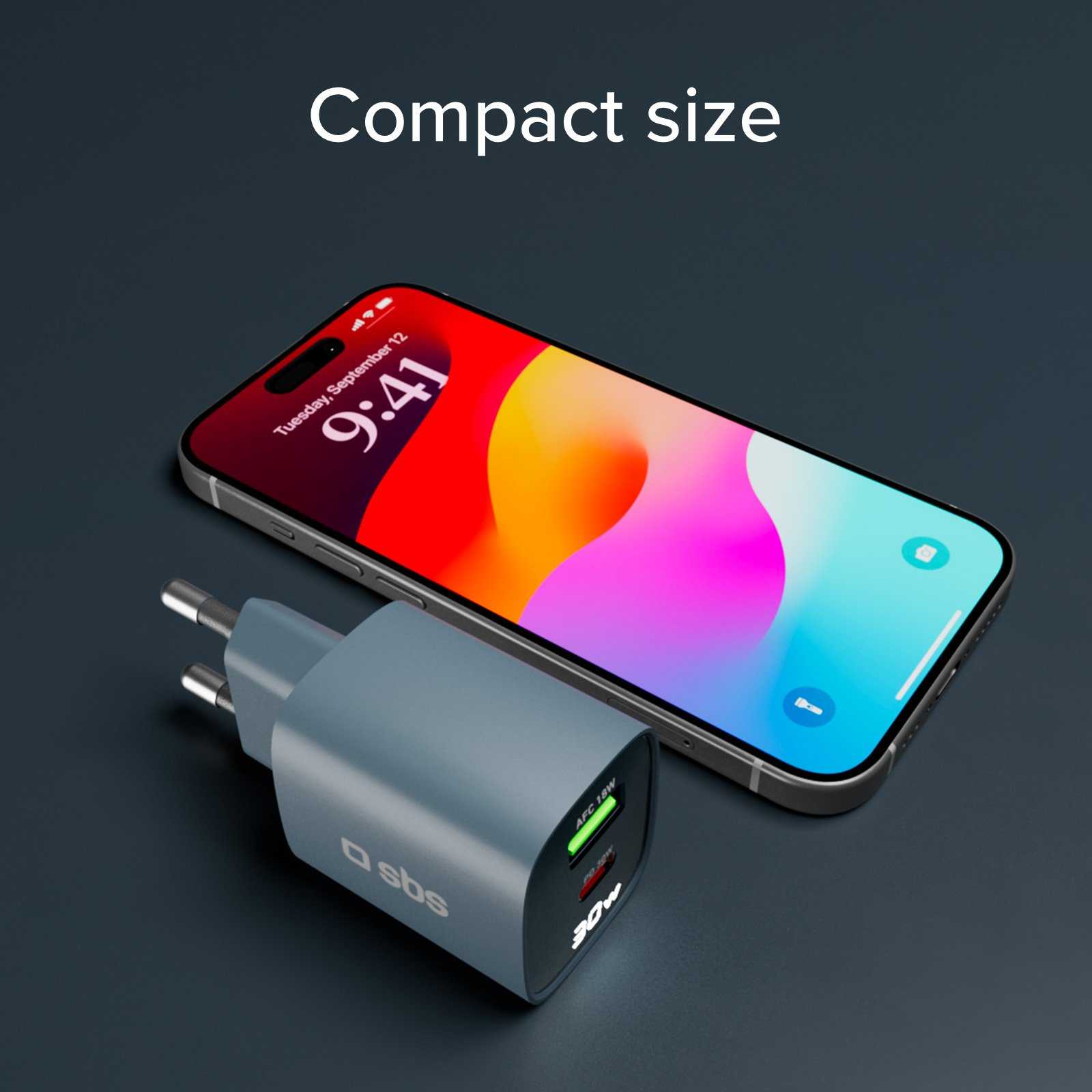 Telefon obok ładowarki. Telefon wyświetla godzinę. Ładowarka jest szara.