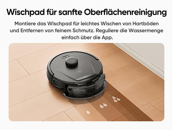 Ein schwarzer Roboterstaubsauger steht auf einem Holzboden, Wassertropfen sind sichtbar. Der Staubsauger hat ein Reinigungspad.