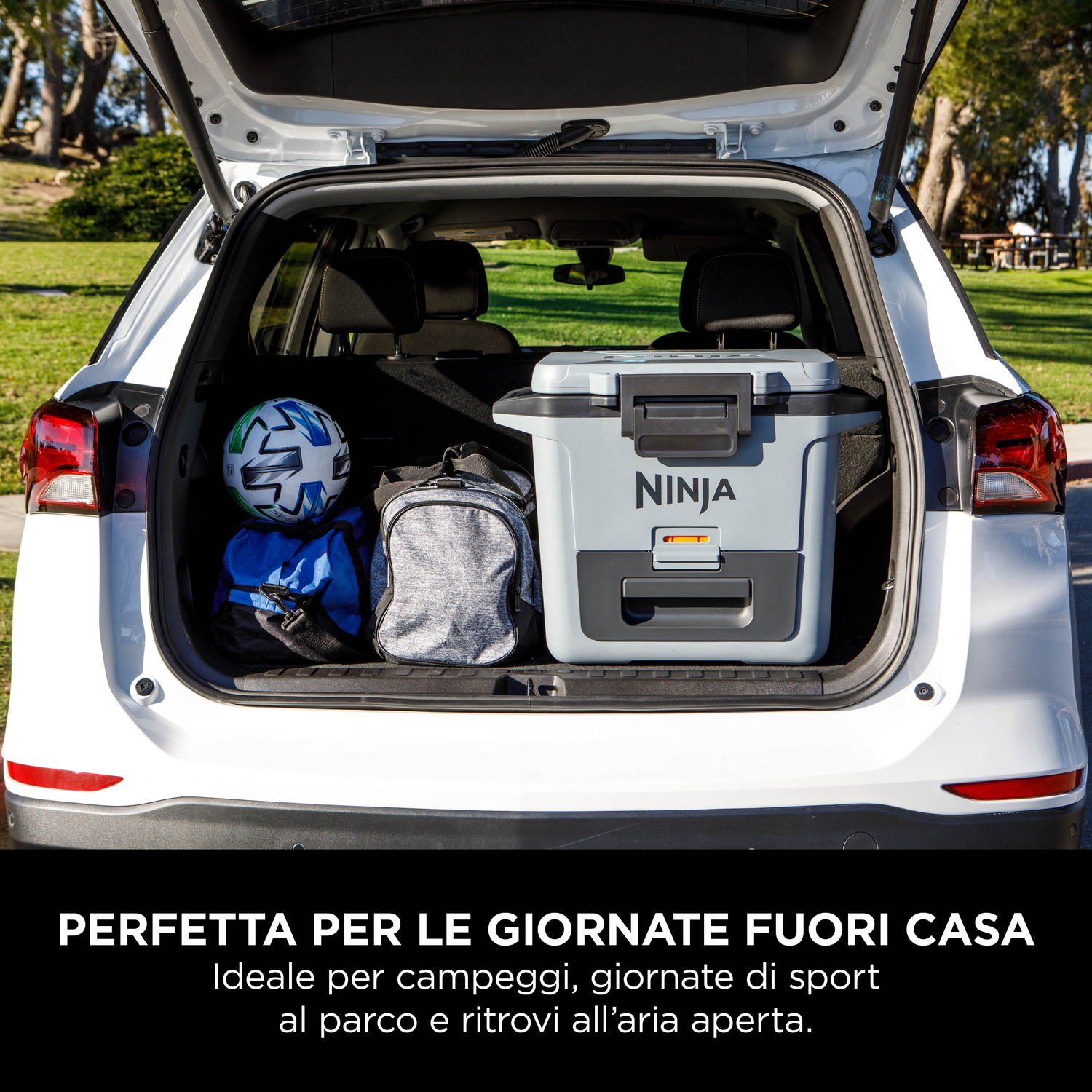 Bagagliaio auto bianco con frigorifero, borse e pallone da calcio, parcheggiato.