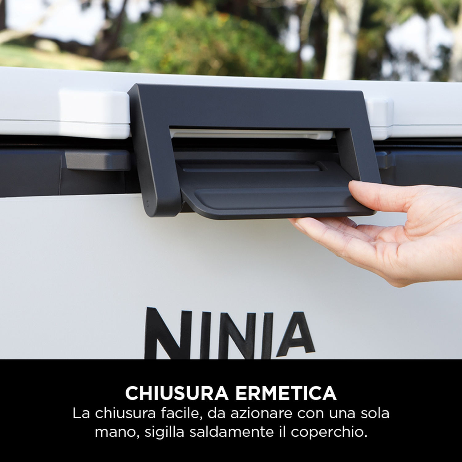 Mano che apre il coperchio nero del frigorifero. Logo Ninja sul frigorifero. Sfondo bianco.