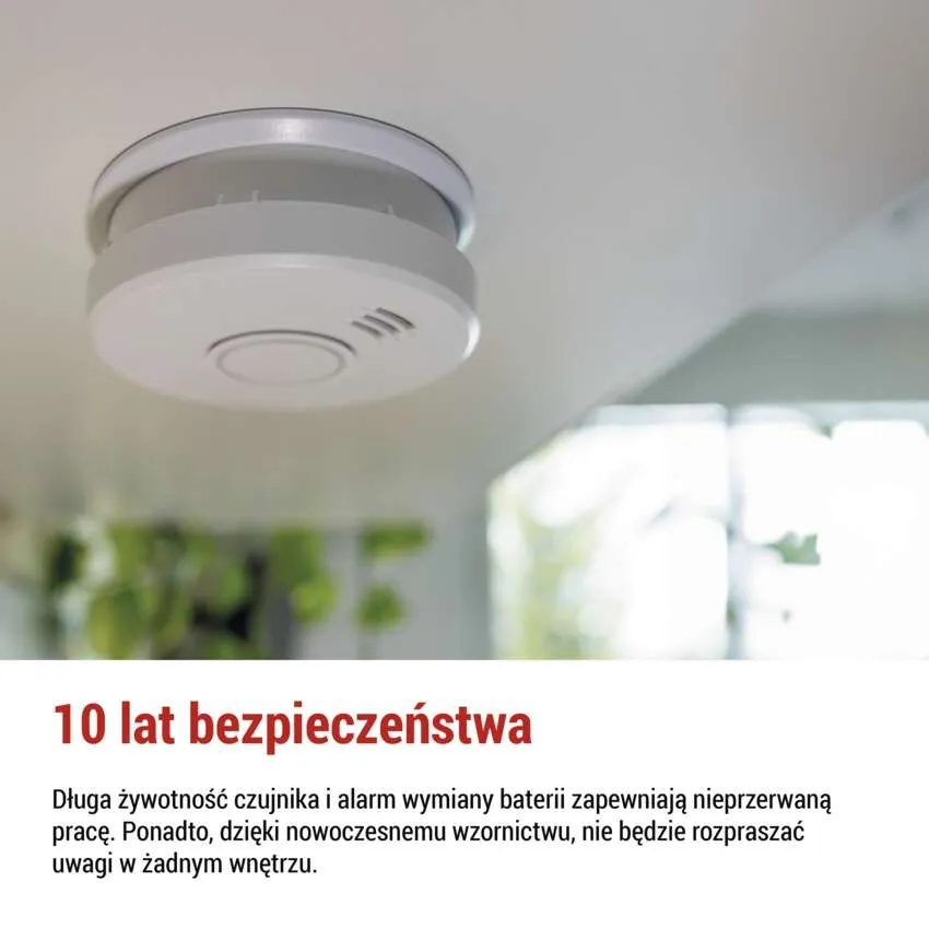 Czujnik dymu na białym suficie. Białe, okrągłe urządzenie, z tekstem i głośnikiem. Tło jest rozmyte.