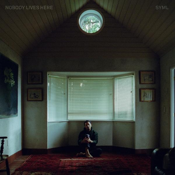 Albumcover. Mann sitzt in Raum mit Fenster, Titel: "NOBODY LIVES HERE".