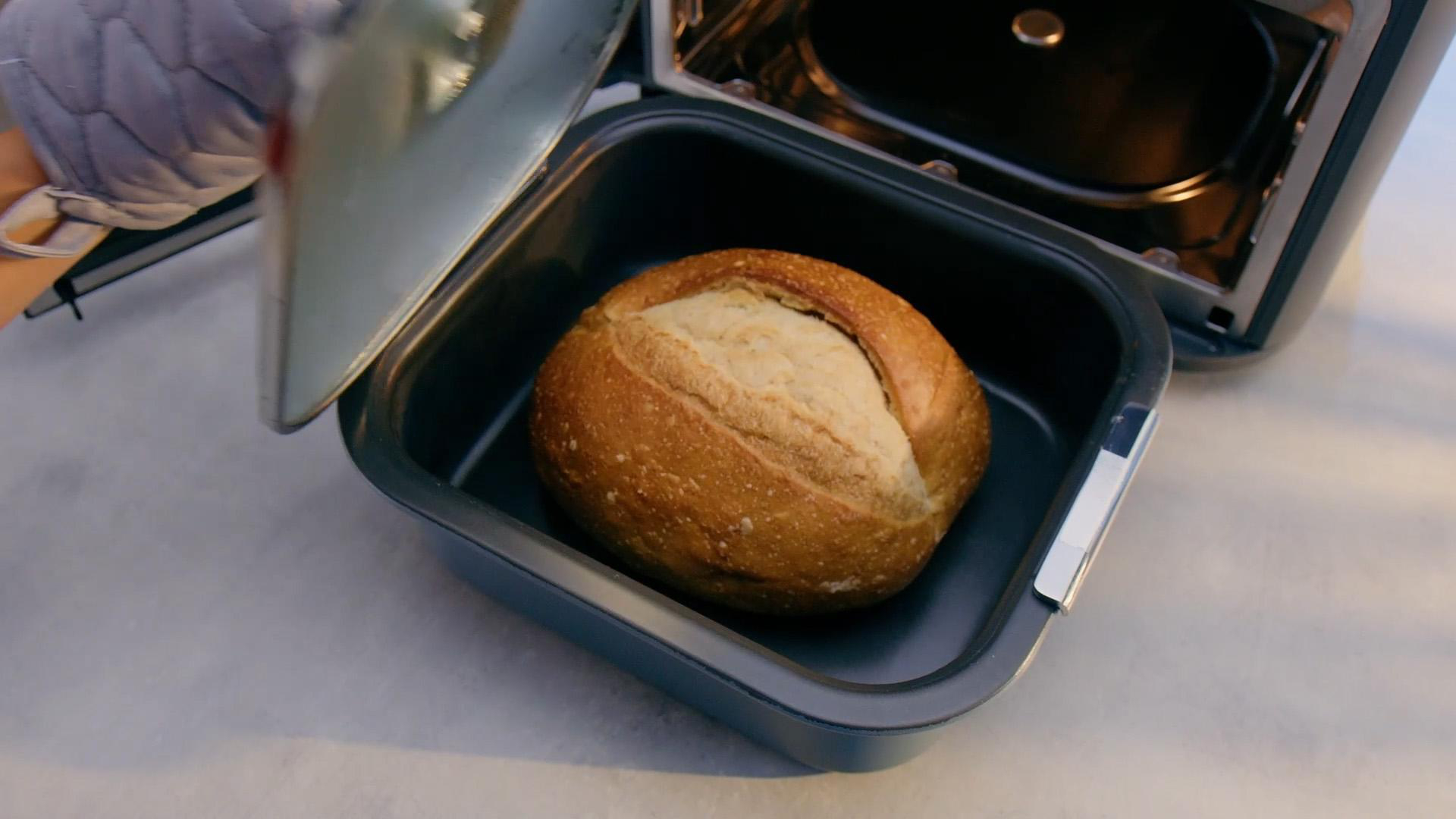 Frisch gebackenes Brot in einer Backform, wird aus einem Gerät genommen.