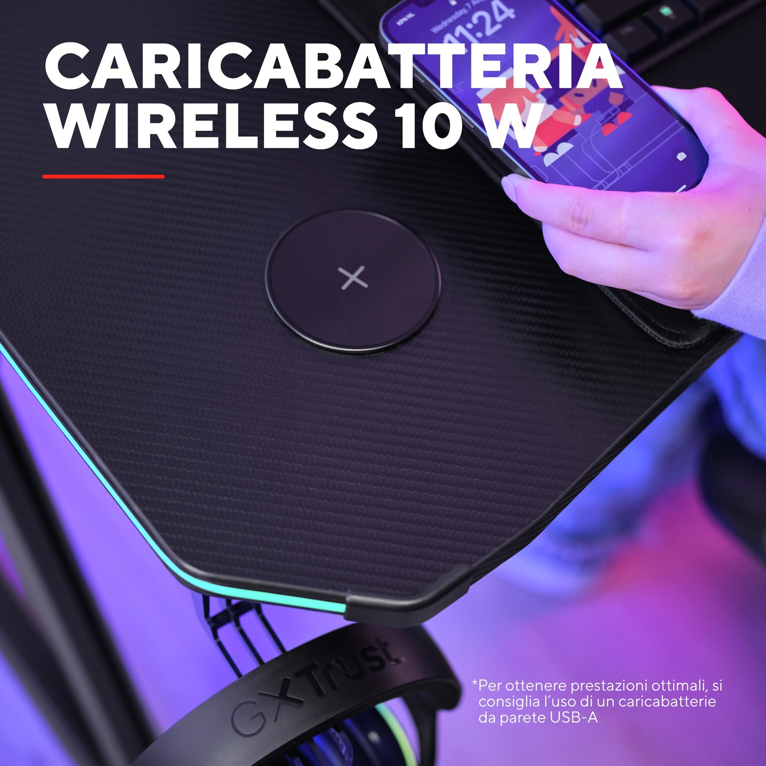 Una persona carica un telefono su un caricatore wireless su una scrivania nera.