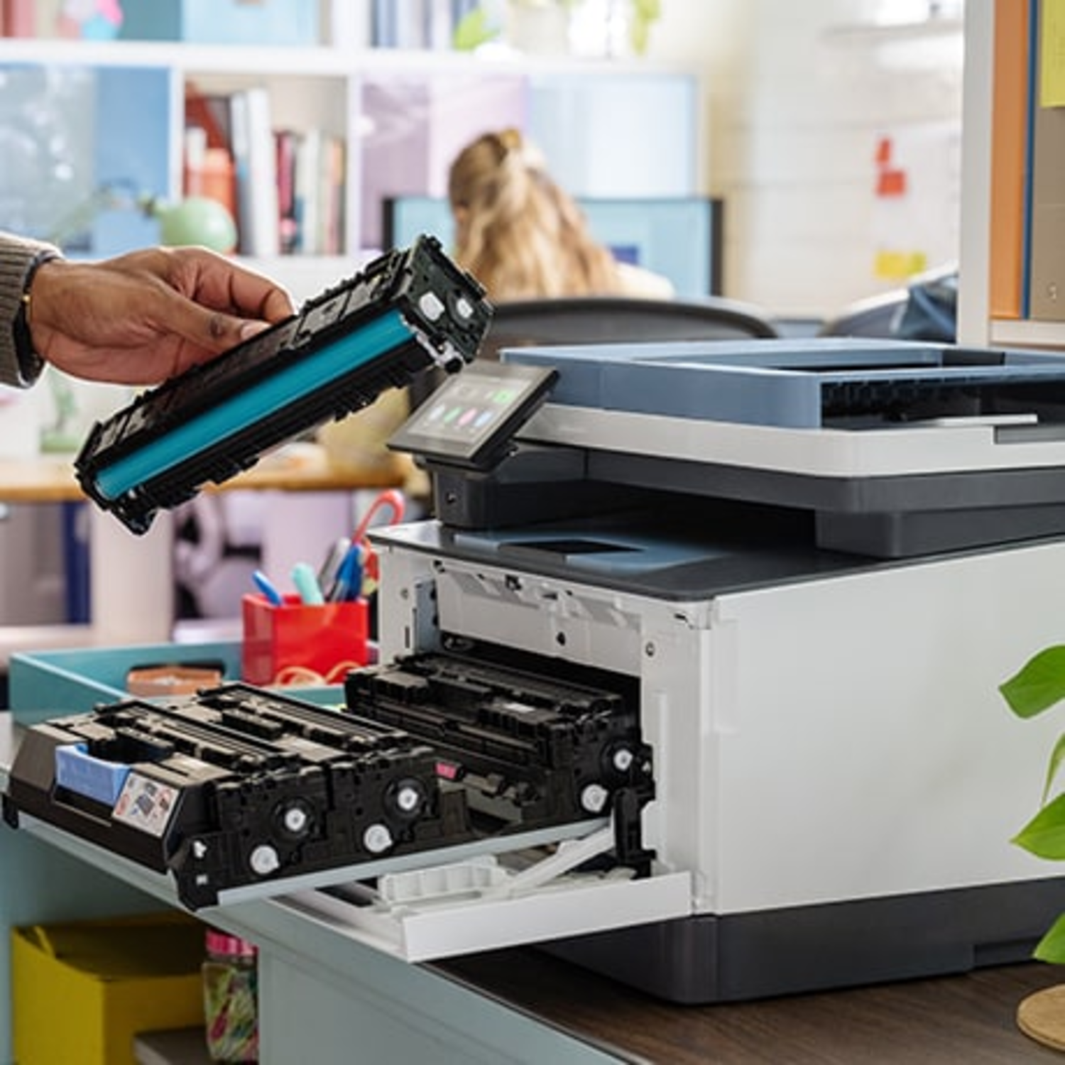 Een persoon vervangt inktcartridges in een printer. Zwarte en blauwe cartridges. Kantoor.