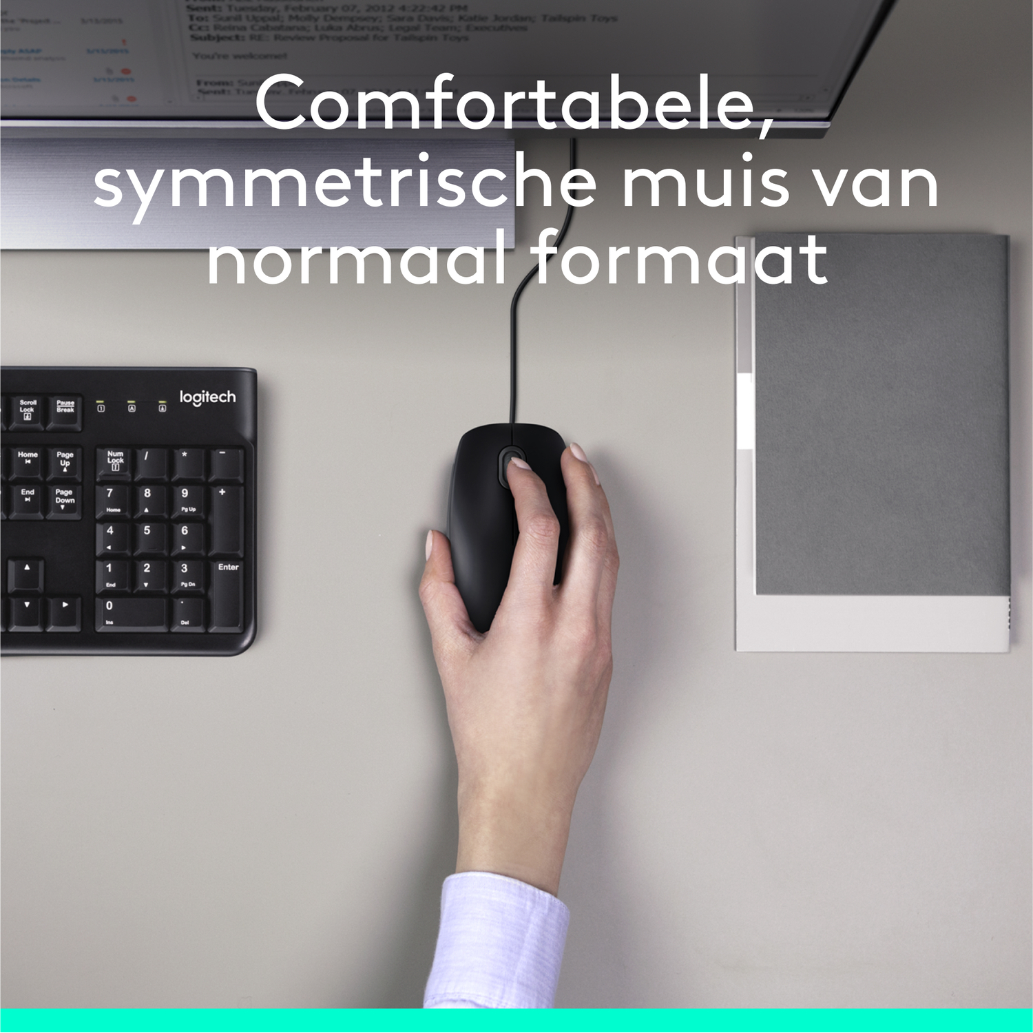 Een hand op een zwarte muis, toetsenbord en papier op een bureau.