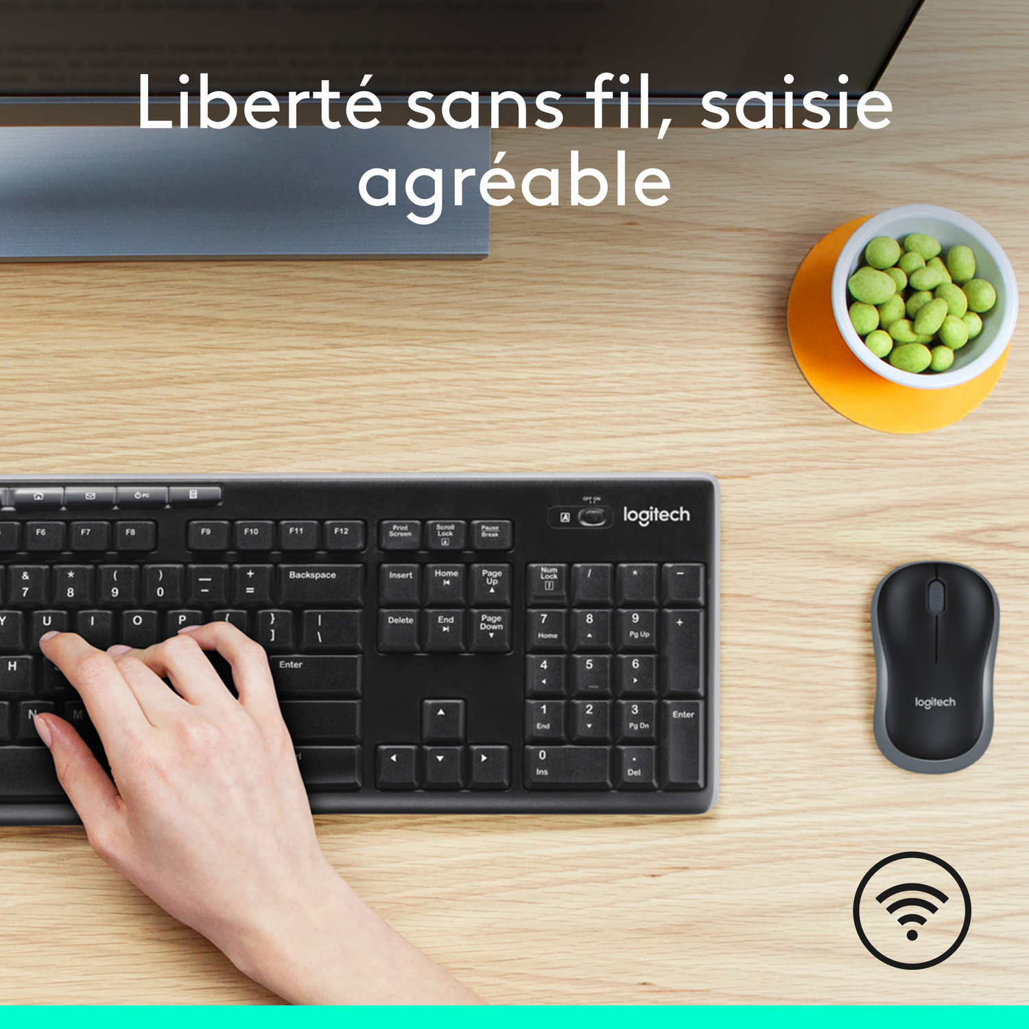 Clavier noir avec une main qui tape. Souris et bol à collation sur une table en bois.