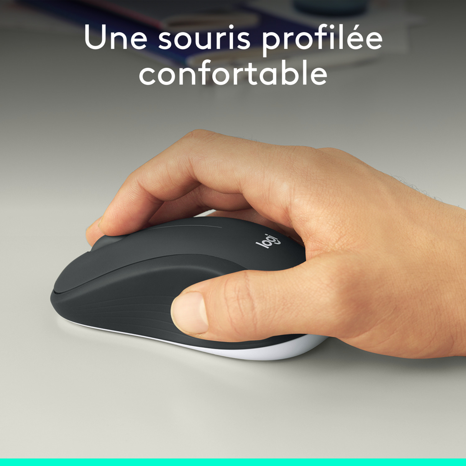 Main tenant une souris sans fil noire avec un fond blanc, sur une surface claire.